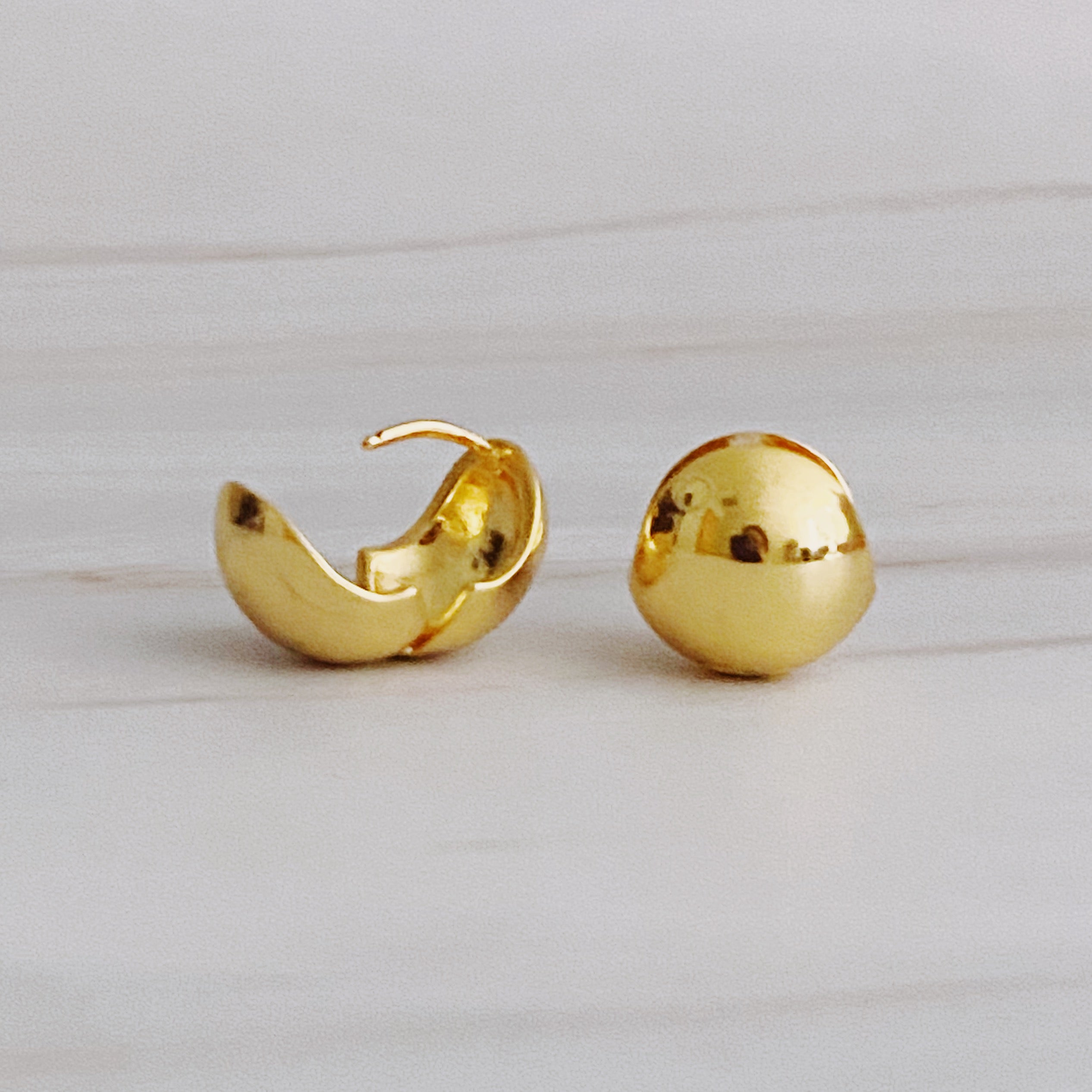 A pair of Seamlessly Round Stud Hoop Earrings in polished gold and silver finishes, showcasing their elegant and chic design.