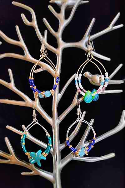 A pair of large seed bead earrings featuring vibrant colors and intricate designs, showcasing their unique craftsmanship.