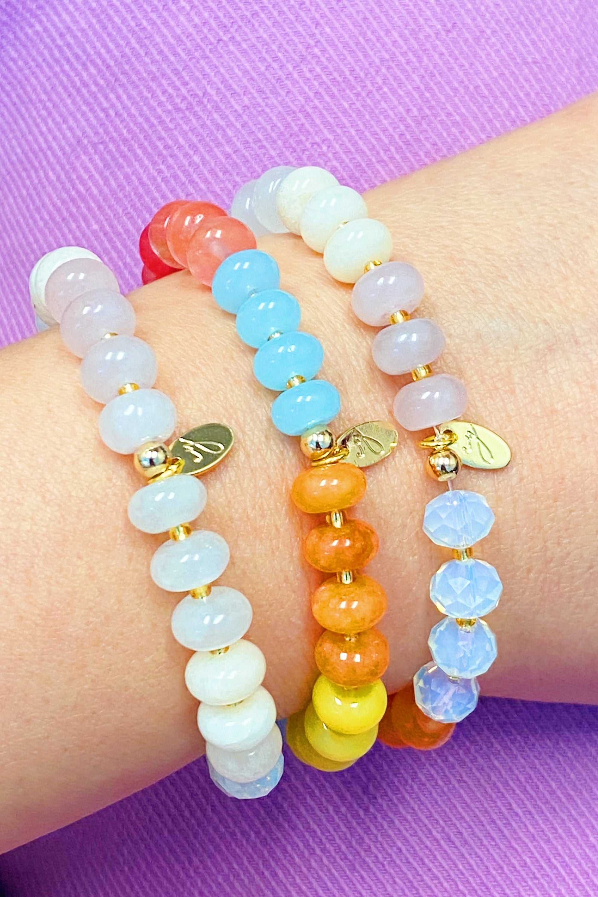 A stylish Semi-Precious Bauble Stretch Bracelet featuring natural stones, beads, and freshwater pearls with a golden logo tag.