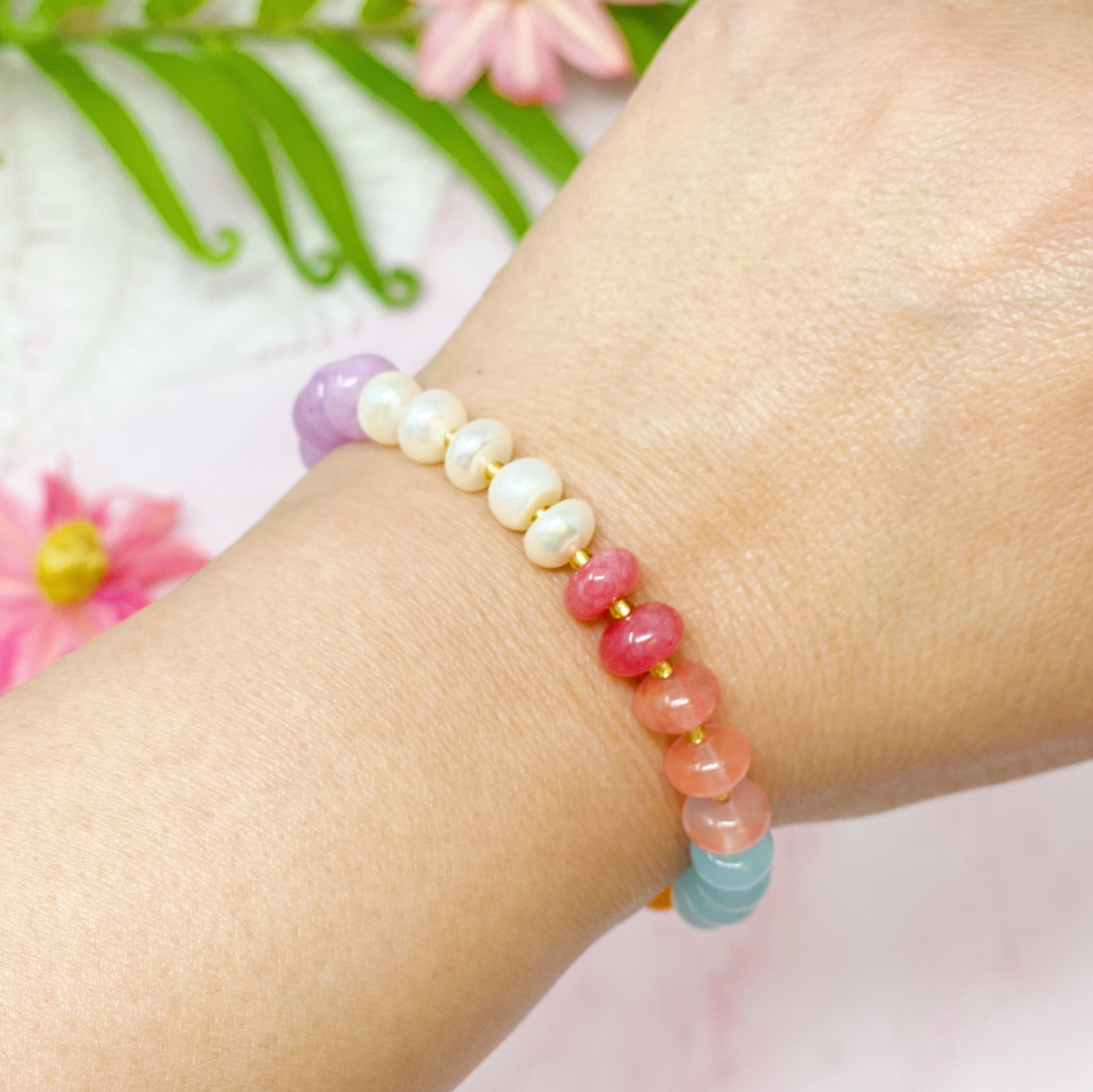 A stylish Semi-Precious Bauble Stretch Bracelet featuring natural stones, beads, and freshwater pearls with a golden logo tag.