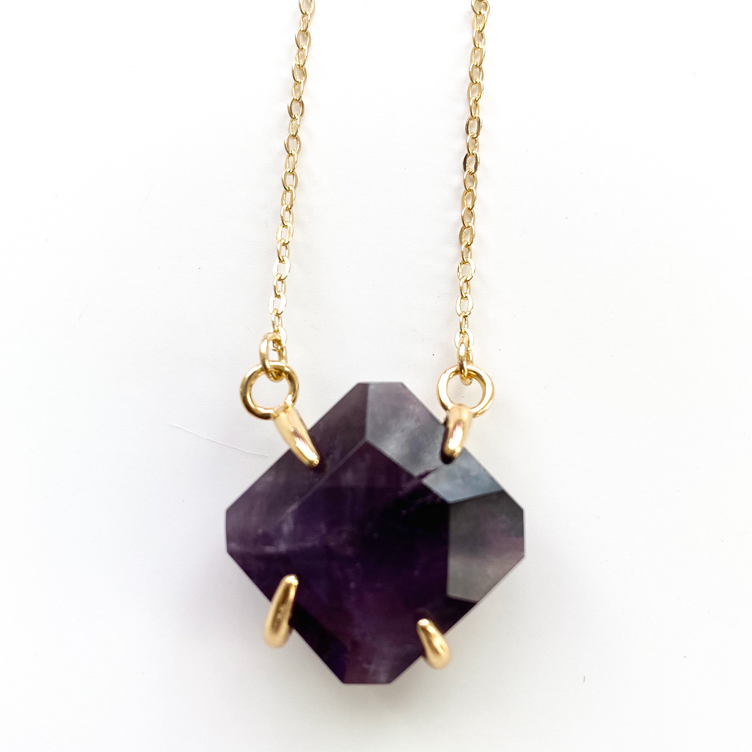 A beautiful handmade necklace featuring a clawed gemstone pendant on an 18K gold plated chain, showcasing elegance and spiritual significance.