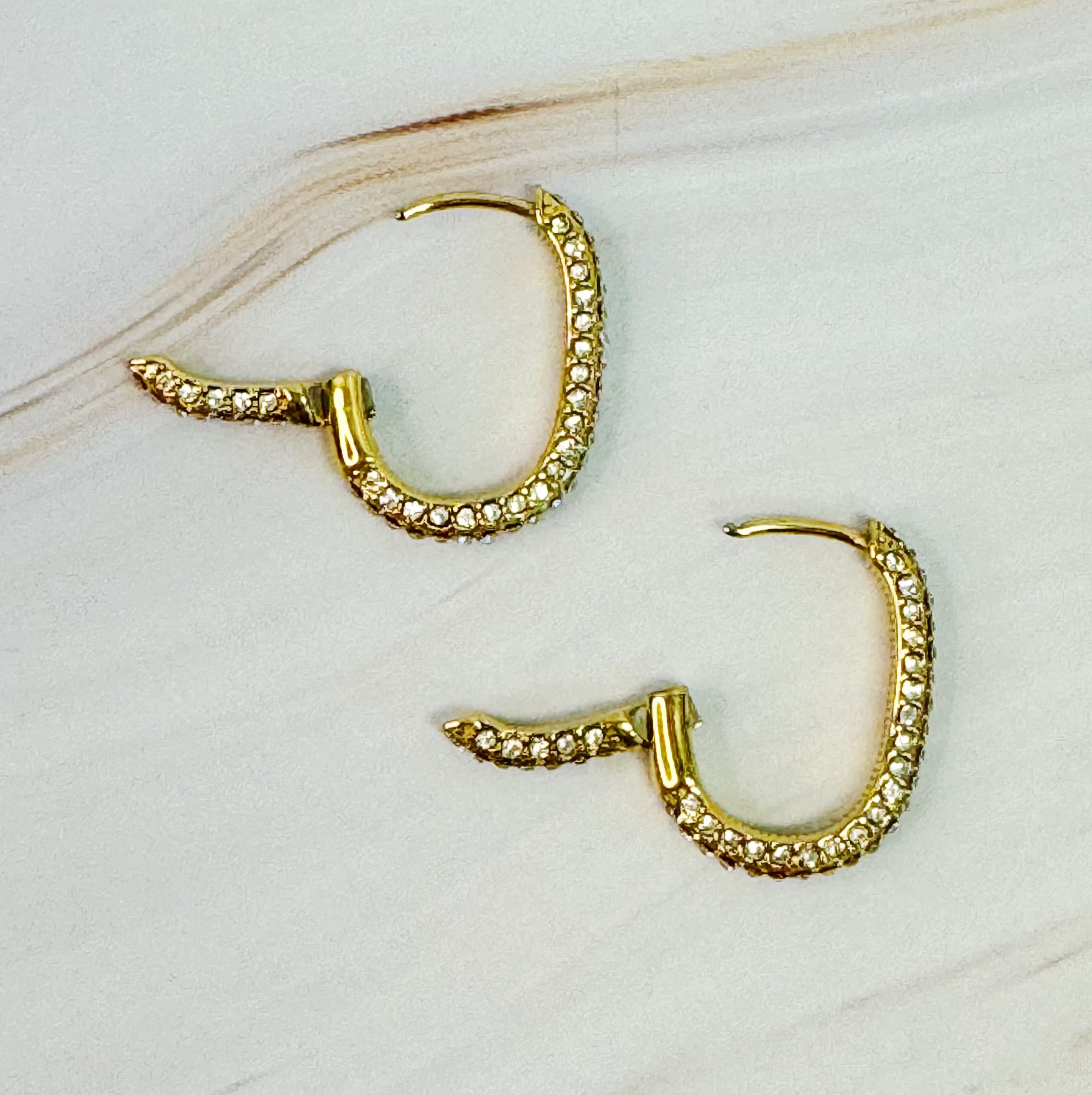 Sophisticated Shine Covered Oval Hoop Earrings in 18k gold plated stainless steel, showcasing their elegant oval shape and shiny finish.