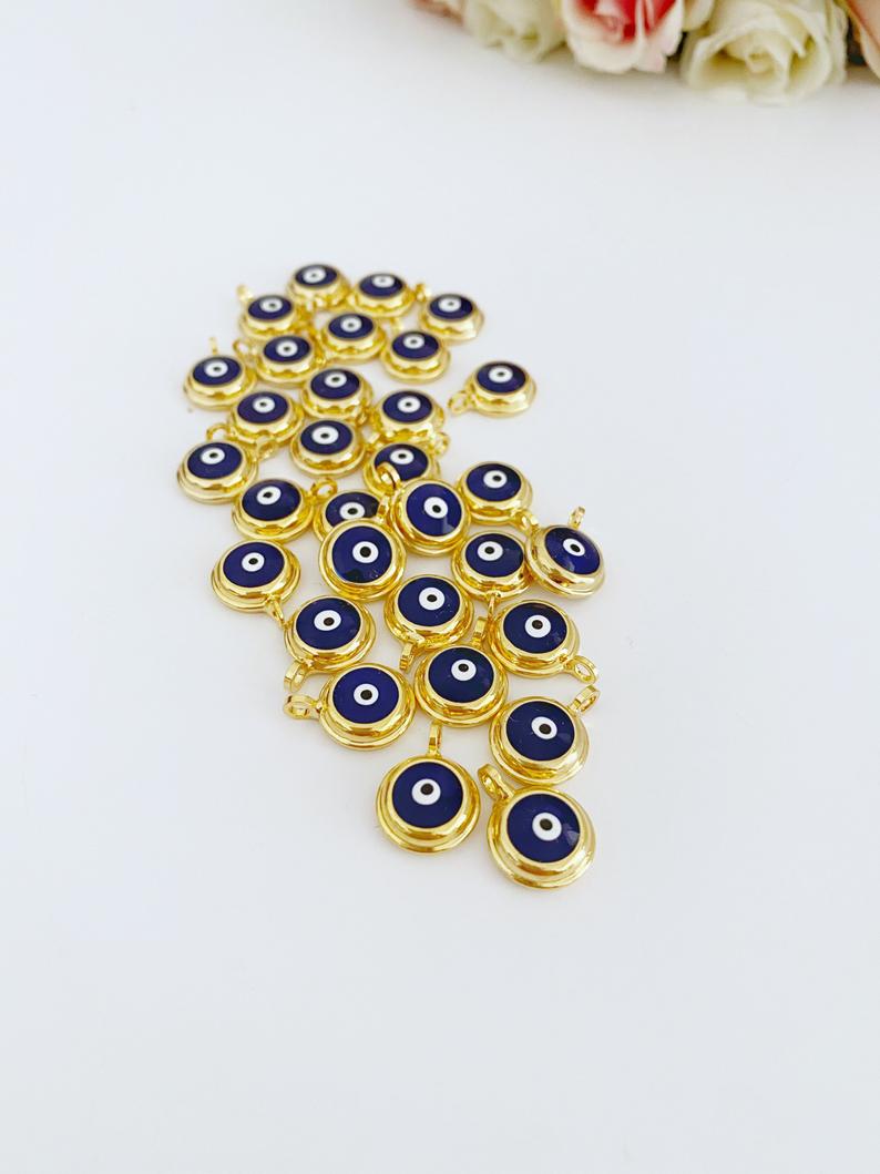 A collection of shiny gold evil eye beads, featuring blue and white designs, perfect for DIY jewelry making.