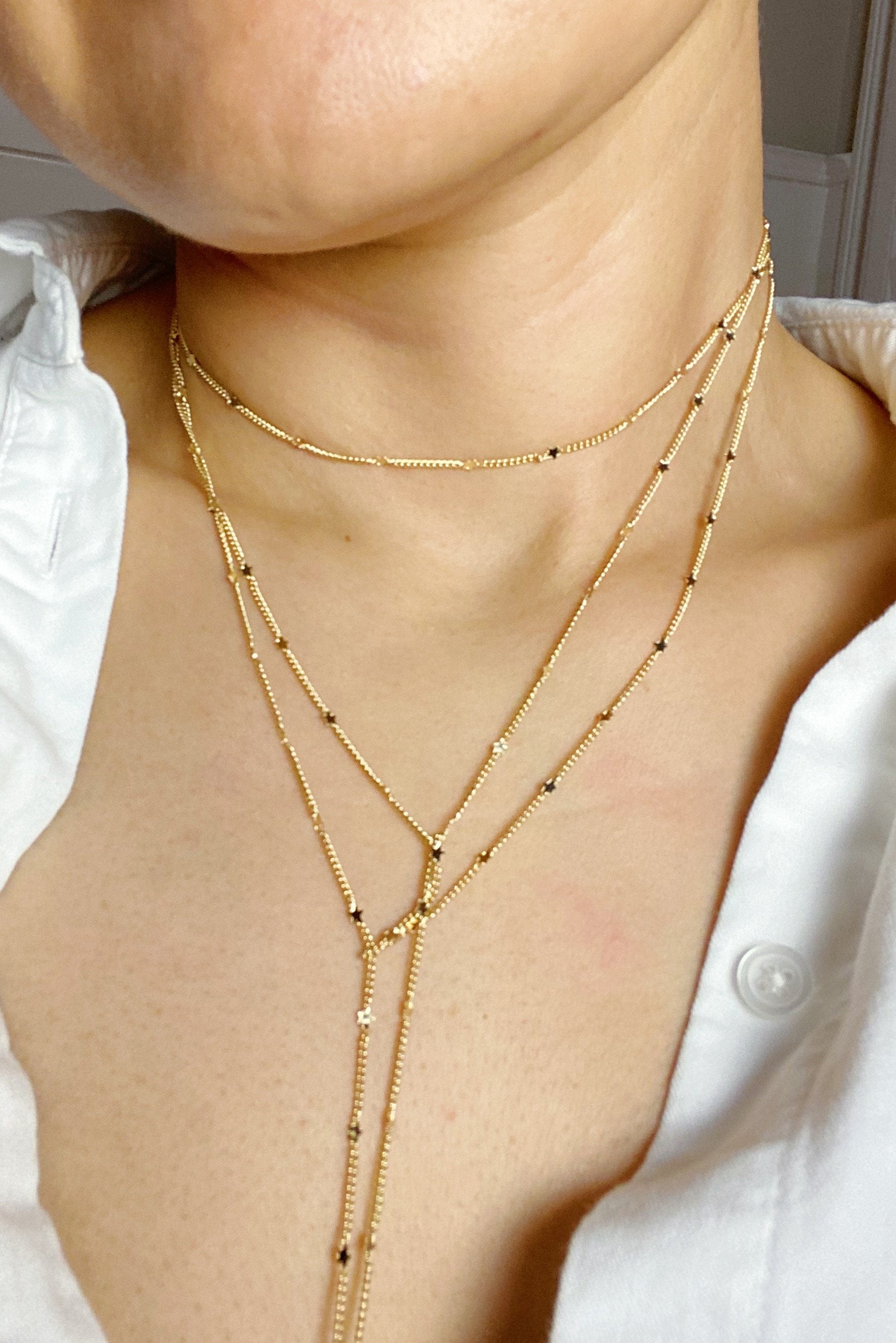 Show Me The Ways Necklace in Gold featuring tiny stars on a long linked chain, showcasing its elegant design and versatility.