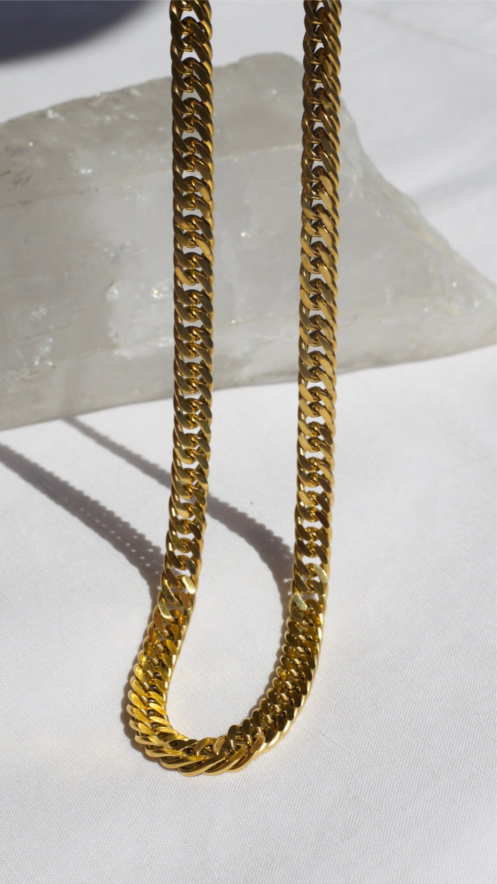 Sienna Cuban Chain Necklace in Gold, featuring a 9mm width and luxurious 18K gold PVD plating, displayed elegantly.