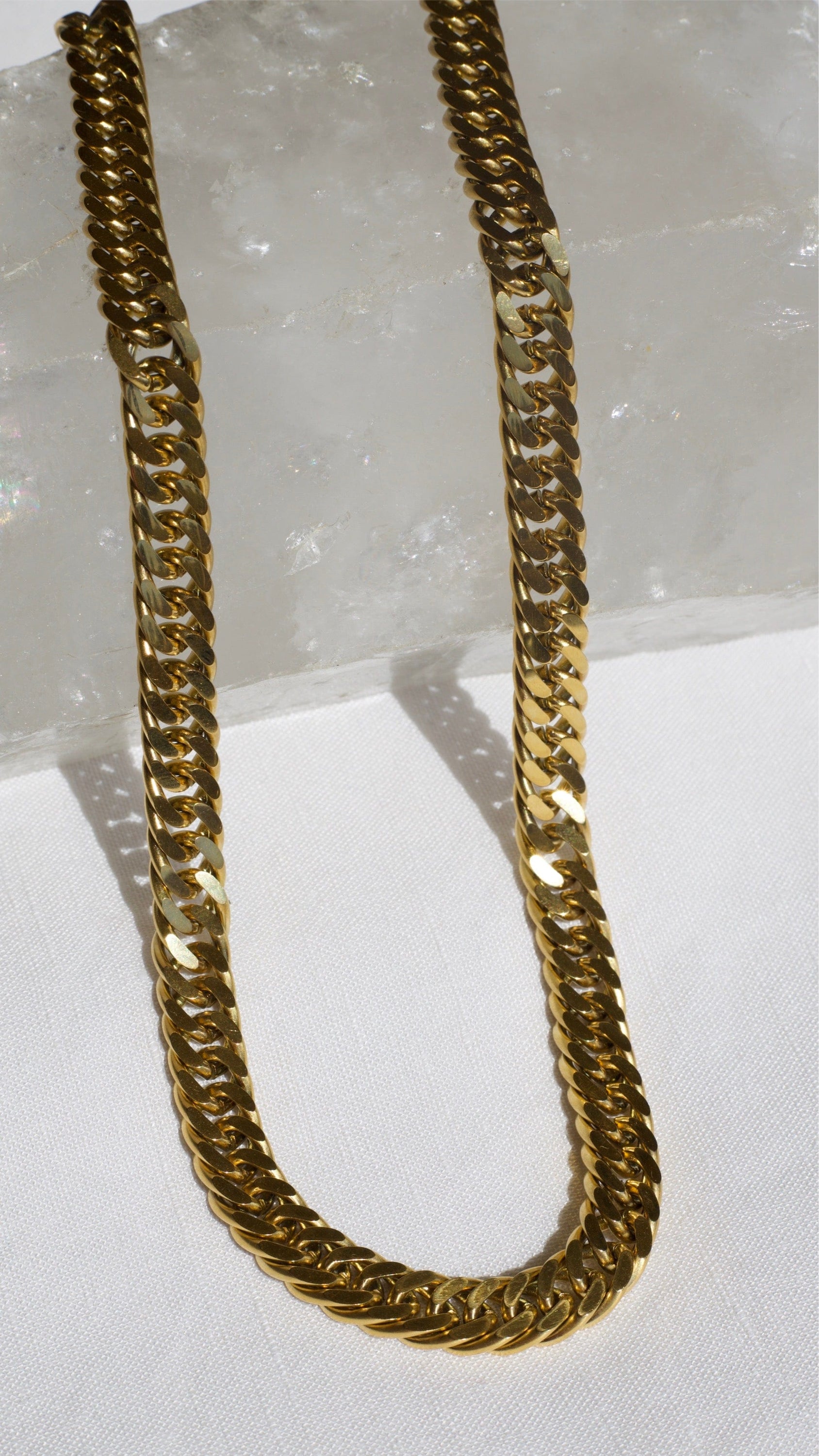 Sienna Cuban Chain Necklace in Gold, featuring a 9mm width and luxurious 18K gold PVD plating, displayed elegantly.