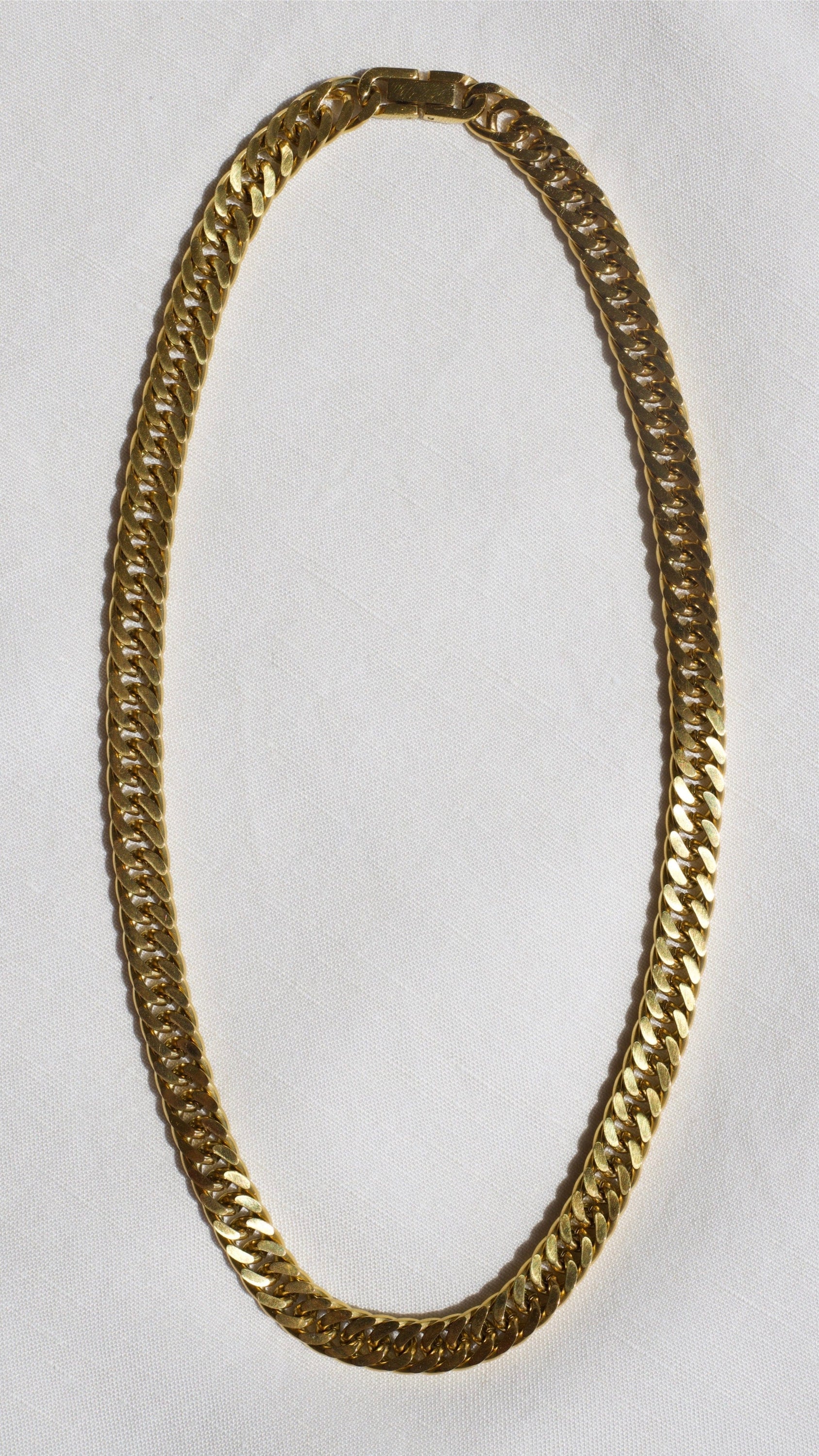 Sienna Cuban Chain Necklace in Gold, featuring a 9mm width and luxurious 18K gold PVD plating, displayed elegantly.