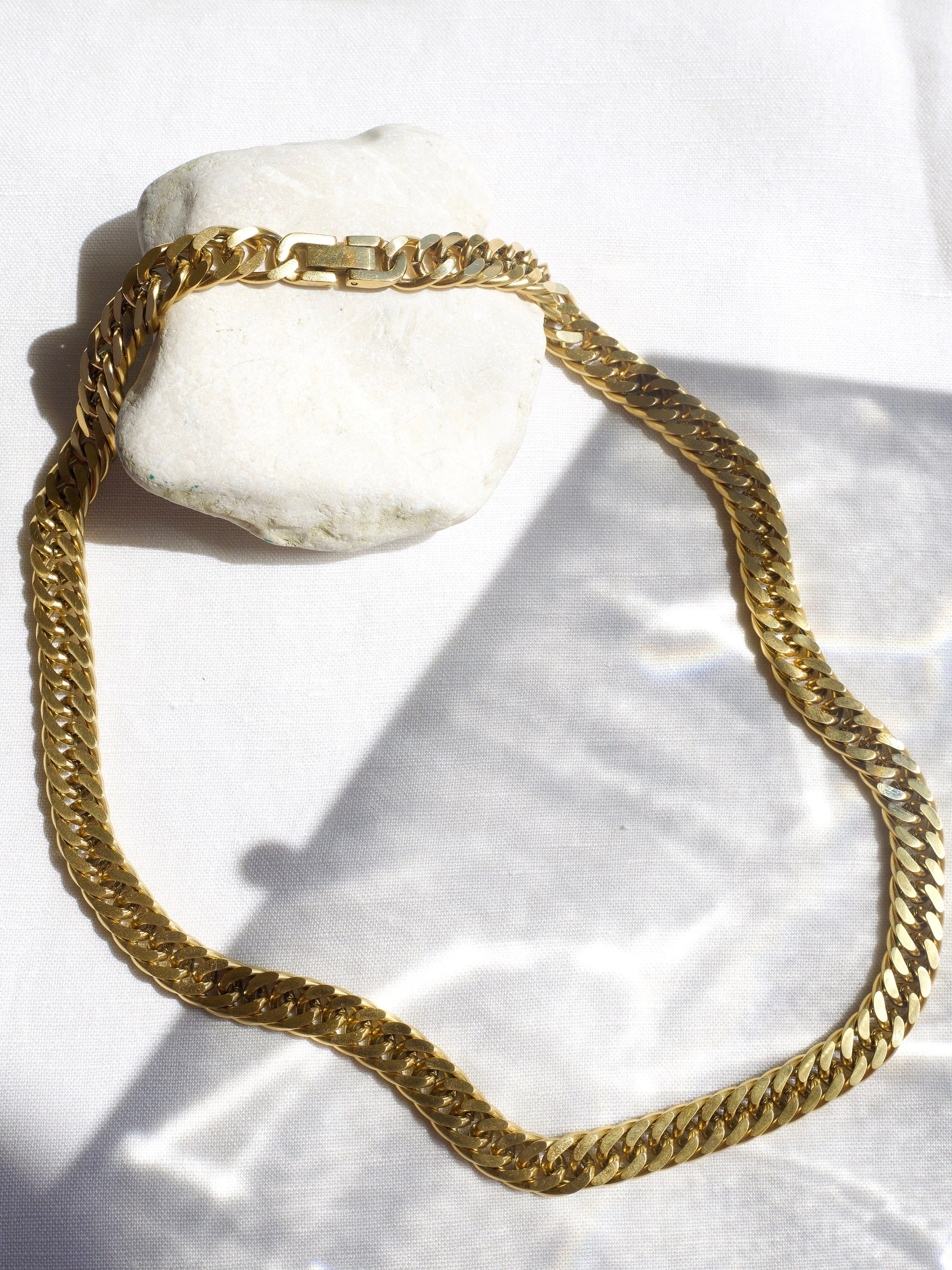 Sienna Cuban Chain Necklace in Gold, featuring a 9mm width and luxurious 18K gold PVD plating, displayed elegantly.