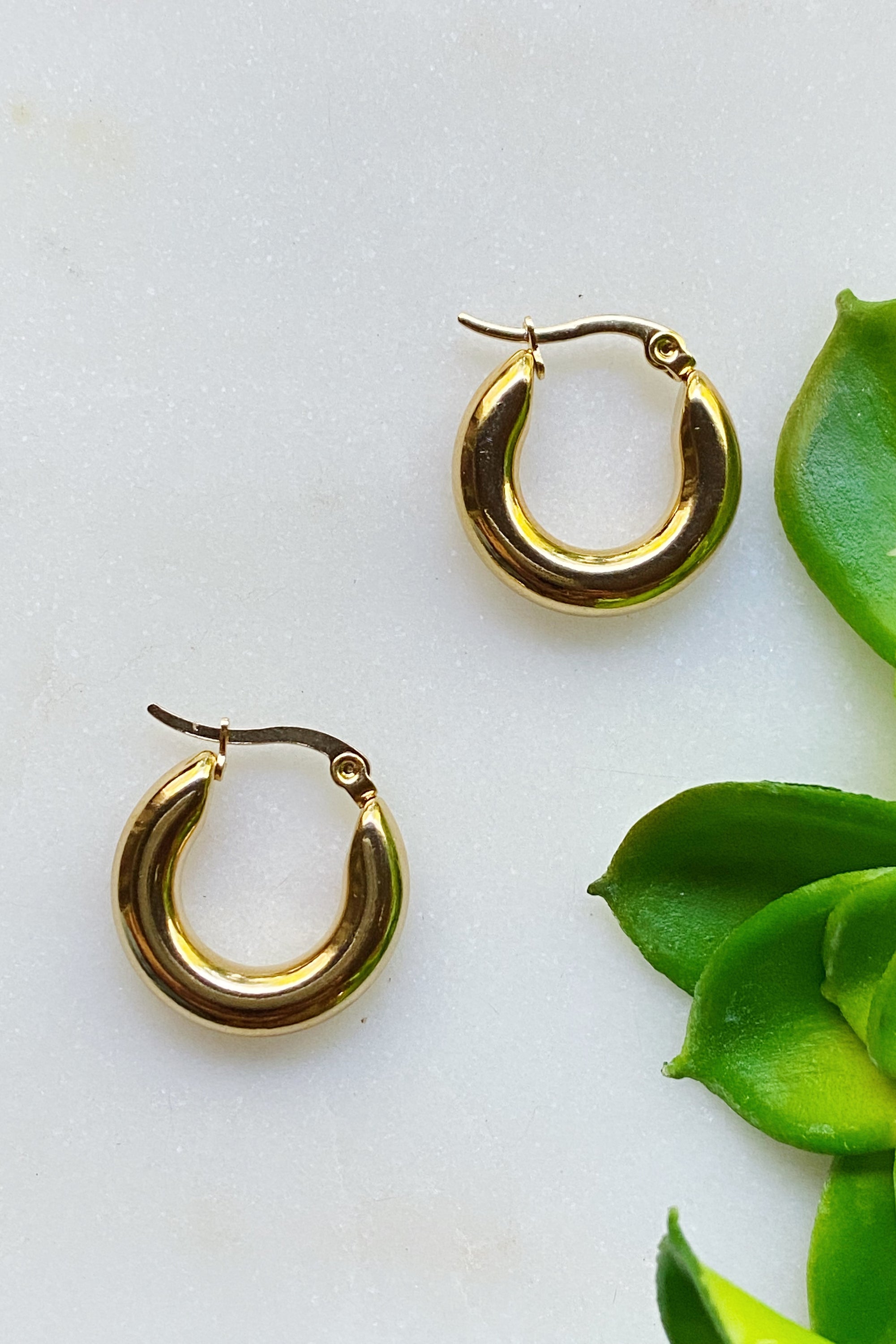 Sienna Huggie Hoop Earrings in polished gold finish, showcasing their small size and elegant design.