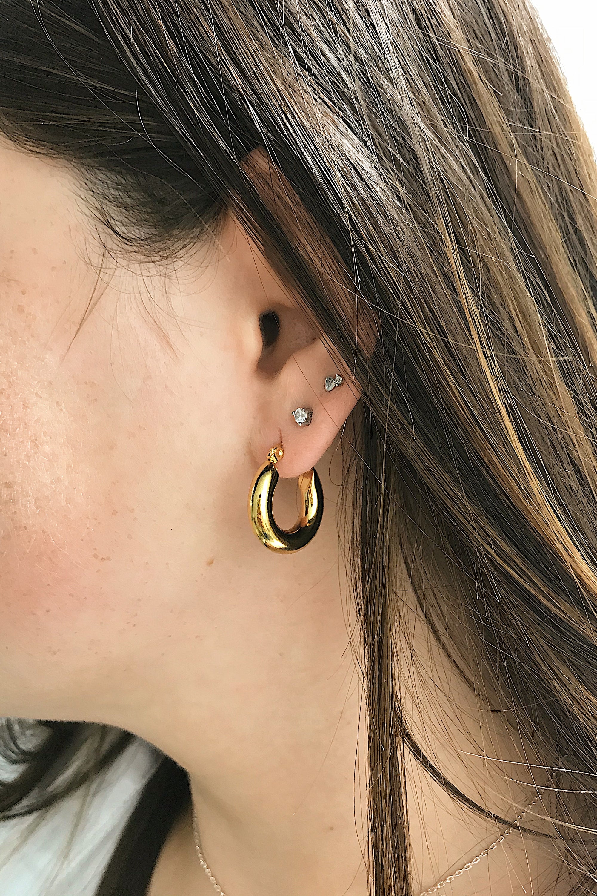 Sienna Huggie Hoop Earrings in polished gold finish, showcasing their small size and elegant design.