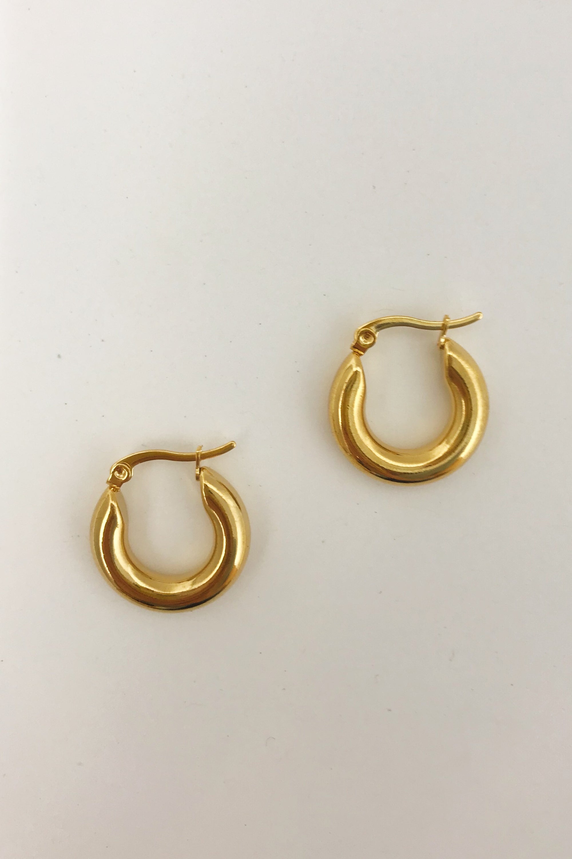 Sienna Huggie Hoop Earrings in polished gold finish, showcasing their small size and elegant design.