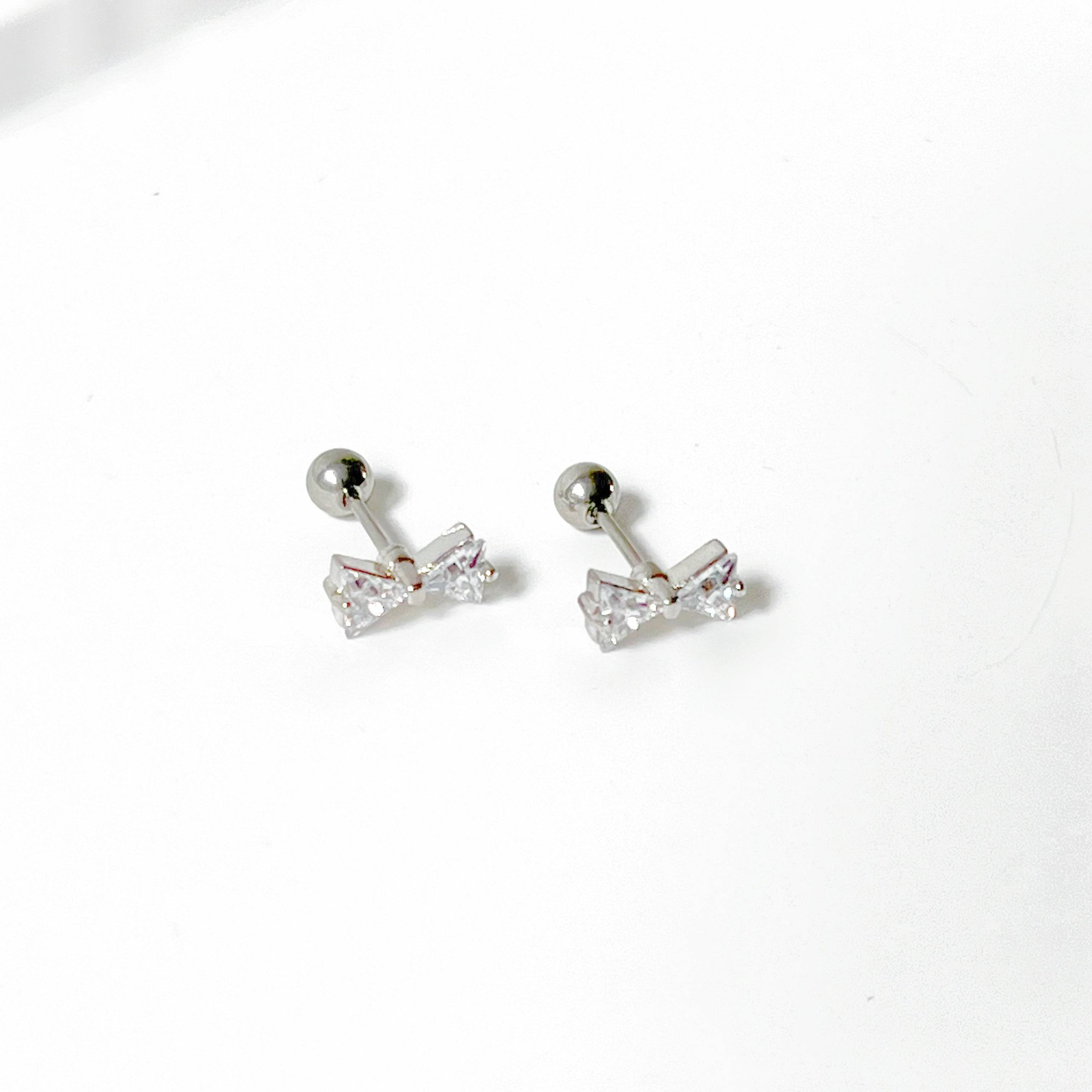 A pair of small silver bow zircon earrings with clear crystals, elegantly designed and hypoallergenic, perfect for gifting.