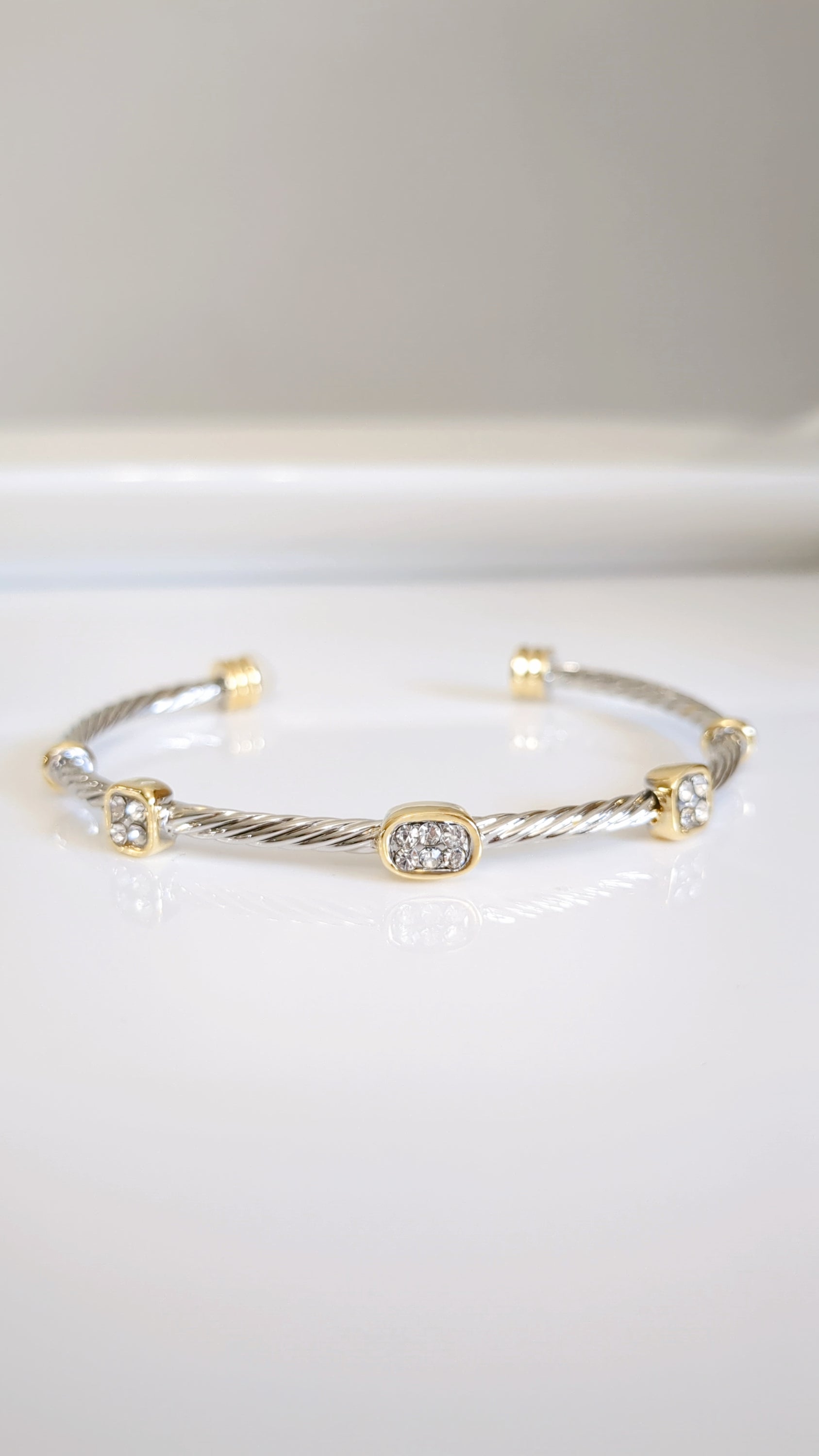 Elegant silver cable bangle adorned with simulated diamonds, showcasing a modern design and lightly adjustable fit.