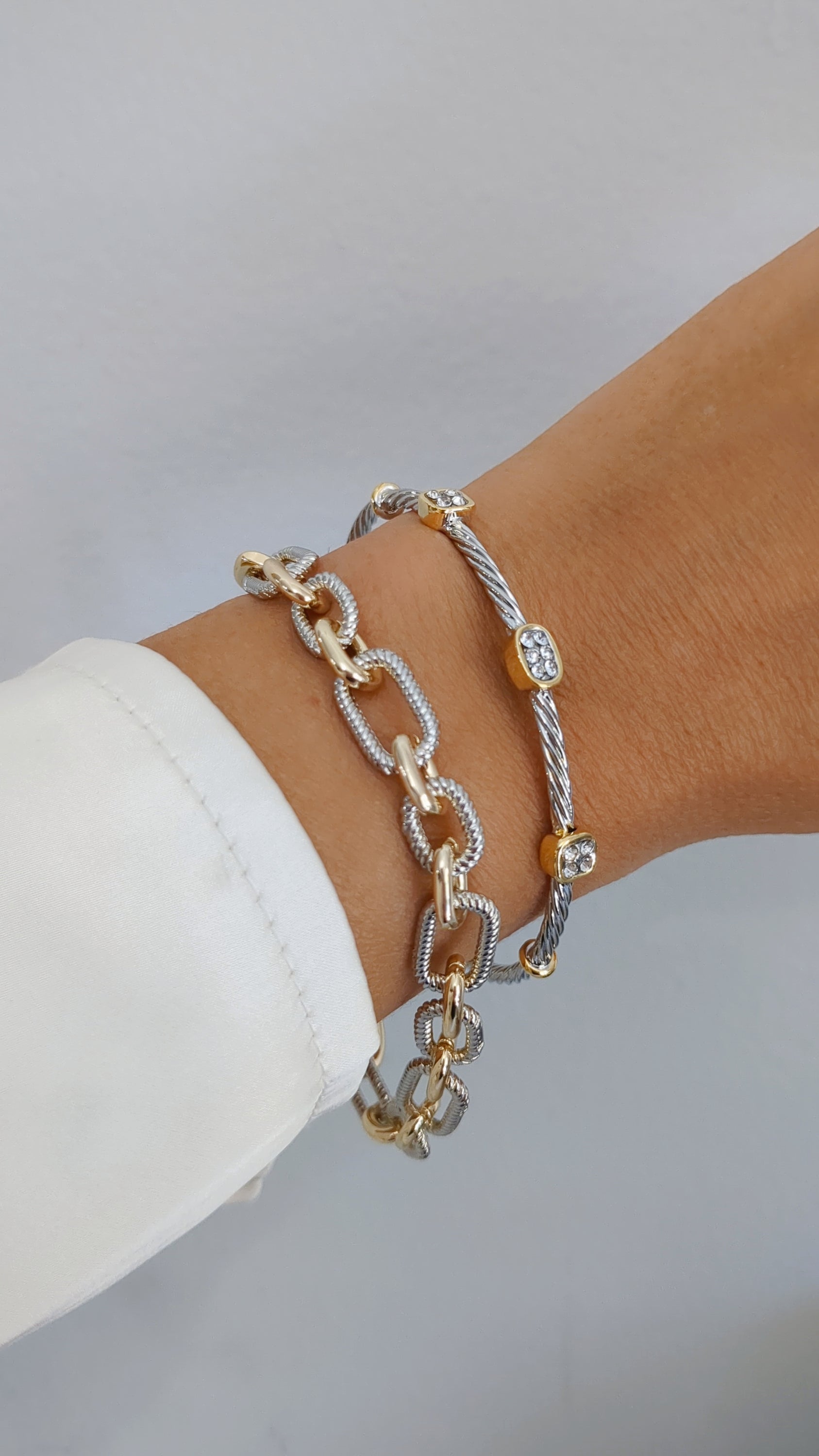 Elegant silver cable bangle adorned with simulated diamonds, showcasing a modern design and lightly adjustable fit.