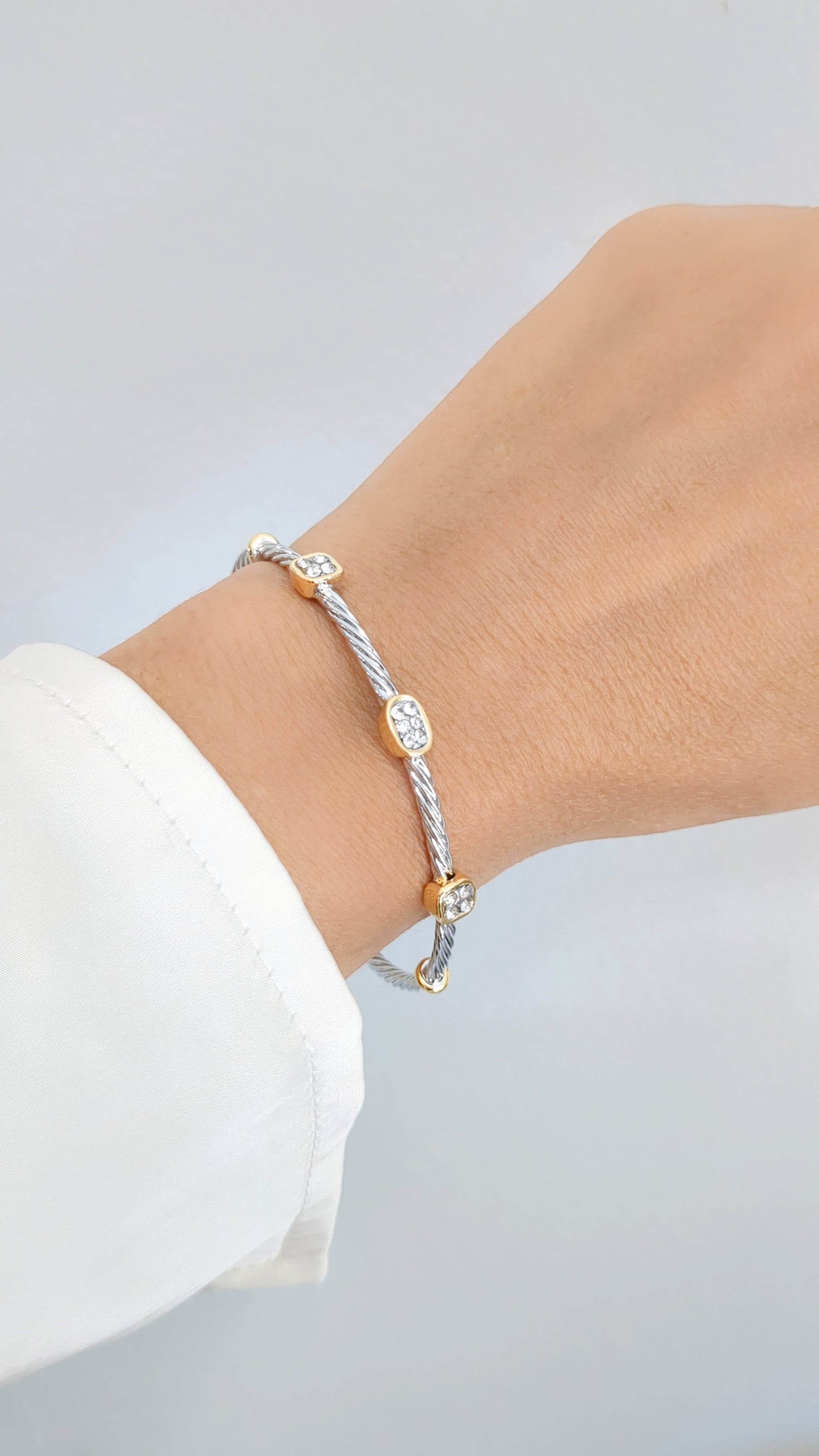 Elegant silver cable bangle adorned with simulated diamonds, showcasing a modern design and lightly adjustable fit.