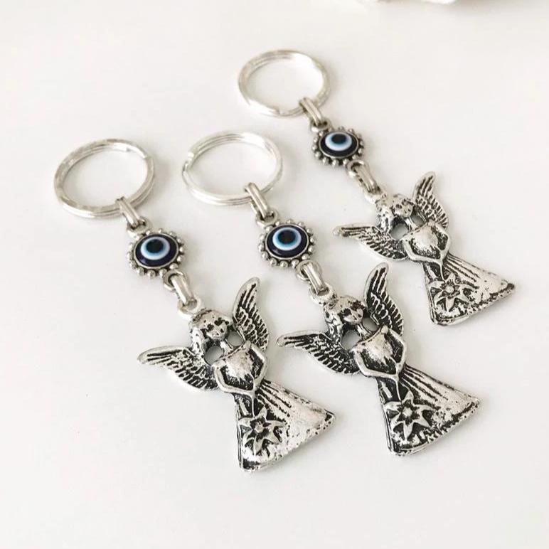 A beautiful silver keychain featuring an evil eye and angel wings, symbolizing protection and good luck.