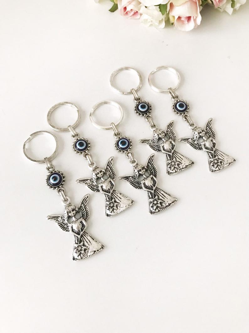 A beautiful silver keychain featuring an evil eye and angel wings, symbolizing protection and good luck.