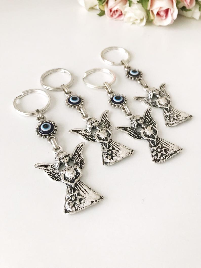 A beautiful silver keychain featuring an evil eye and angel wings, symbolizing protection and good luck.