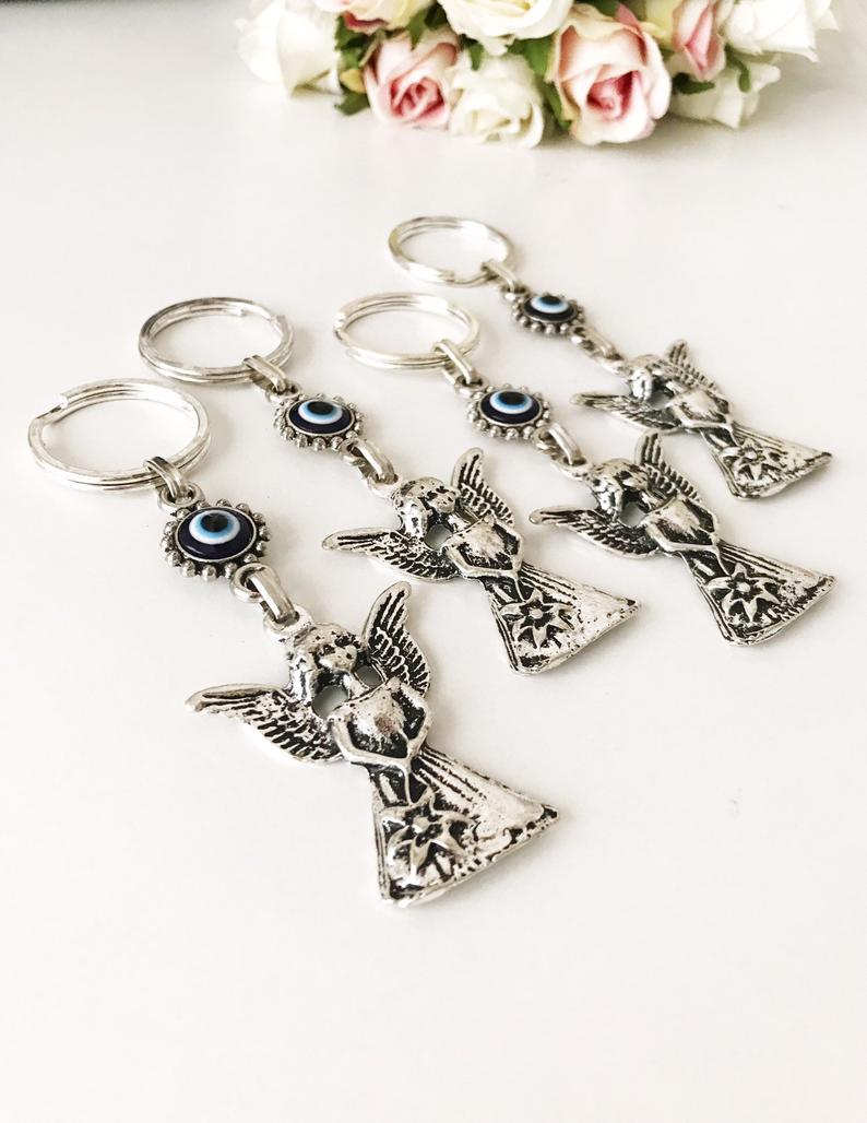 A beautiful silver keychain featuring an evil eye and angel wings, symbolizing protection and good luck.