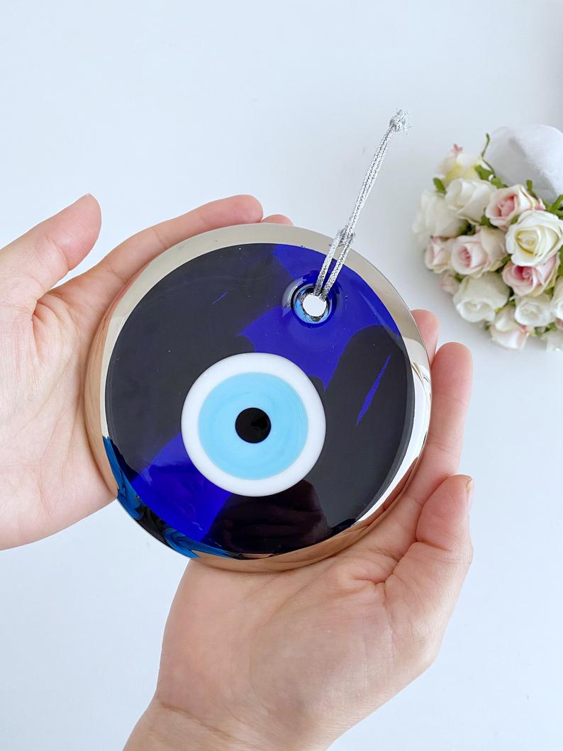 A 13cm silver evil eye bead wall hanging, featuring a blue handmade evil eye design, elegantly crafted for home decor.