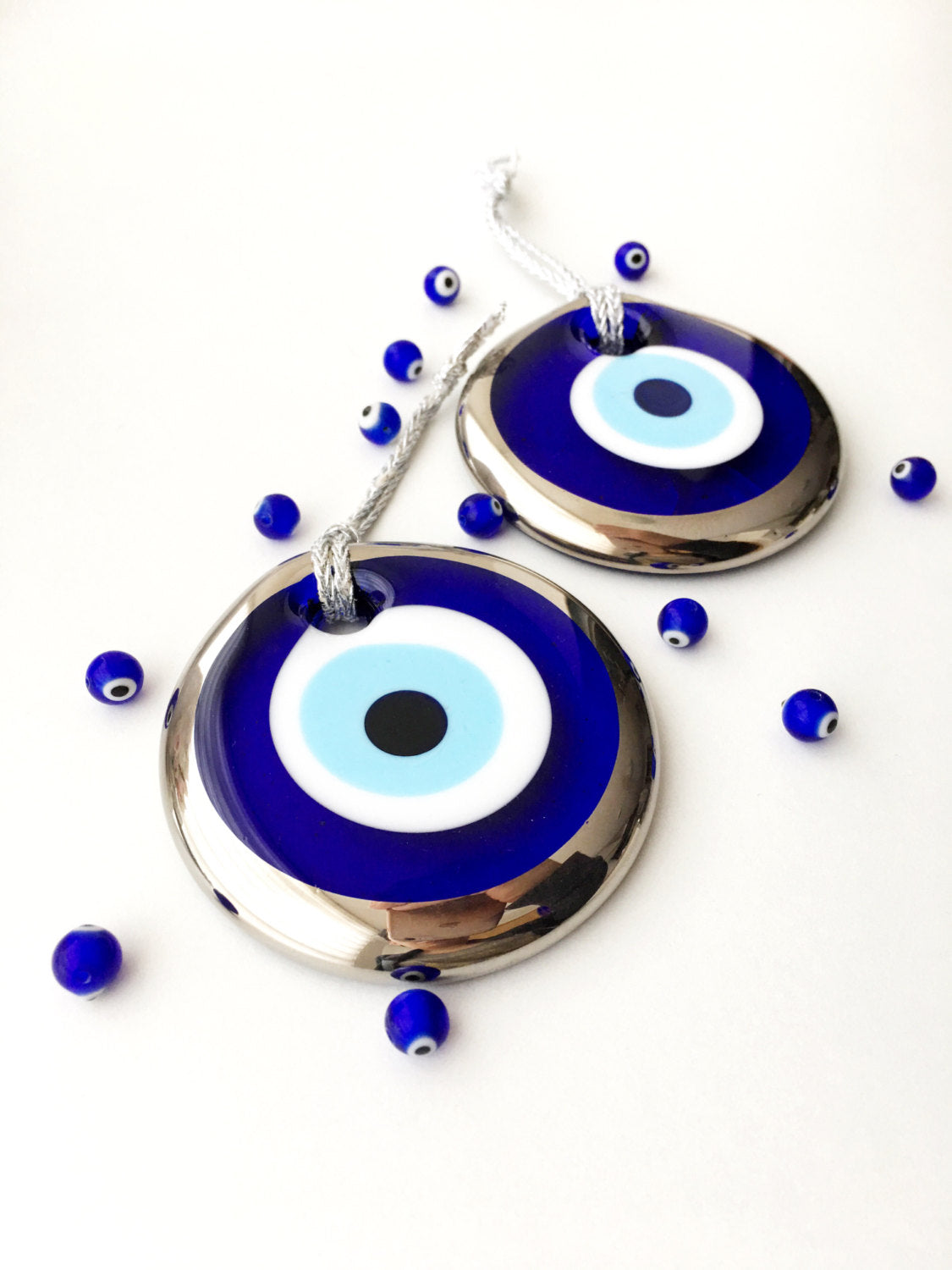 A 7cm silver evil eye bead wall hanging with intricate designs, featuring a silver rope for easy hanging, symbolizing protection and good luck.