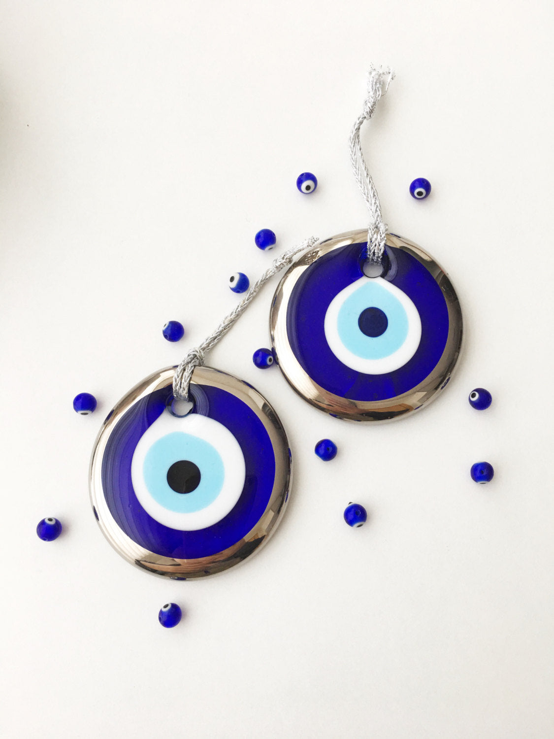 A 7cm silver evil eye bead wall hanging with intricate designs, featuring a silver rope for easy hanging, symbolizing protection and good luck.