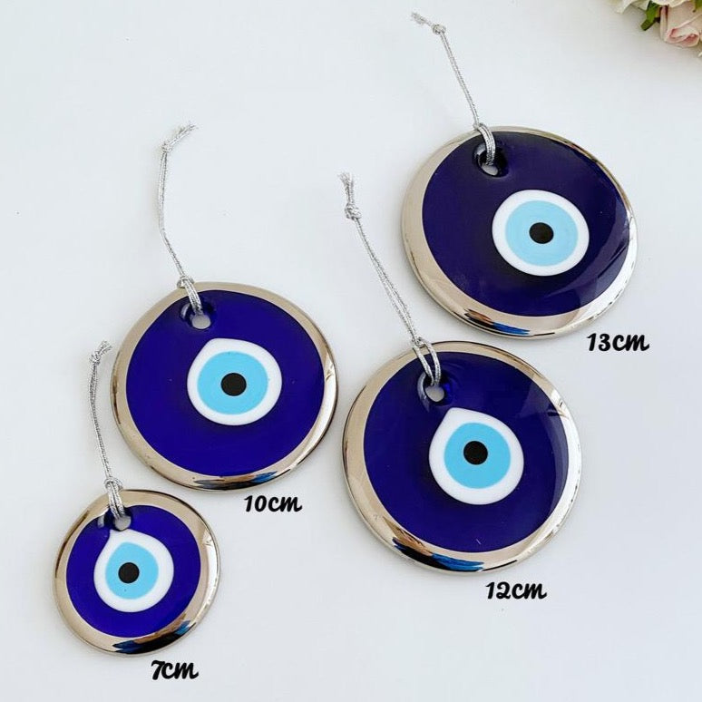 A collection of handmade silver evil eye beads ranging from 7cm to 13cm, showcasing intricate designs and a shiny finish, ready for wall hanging.