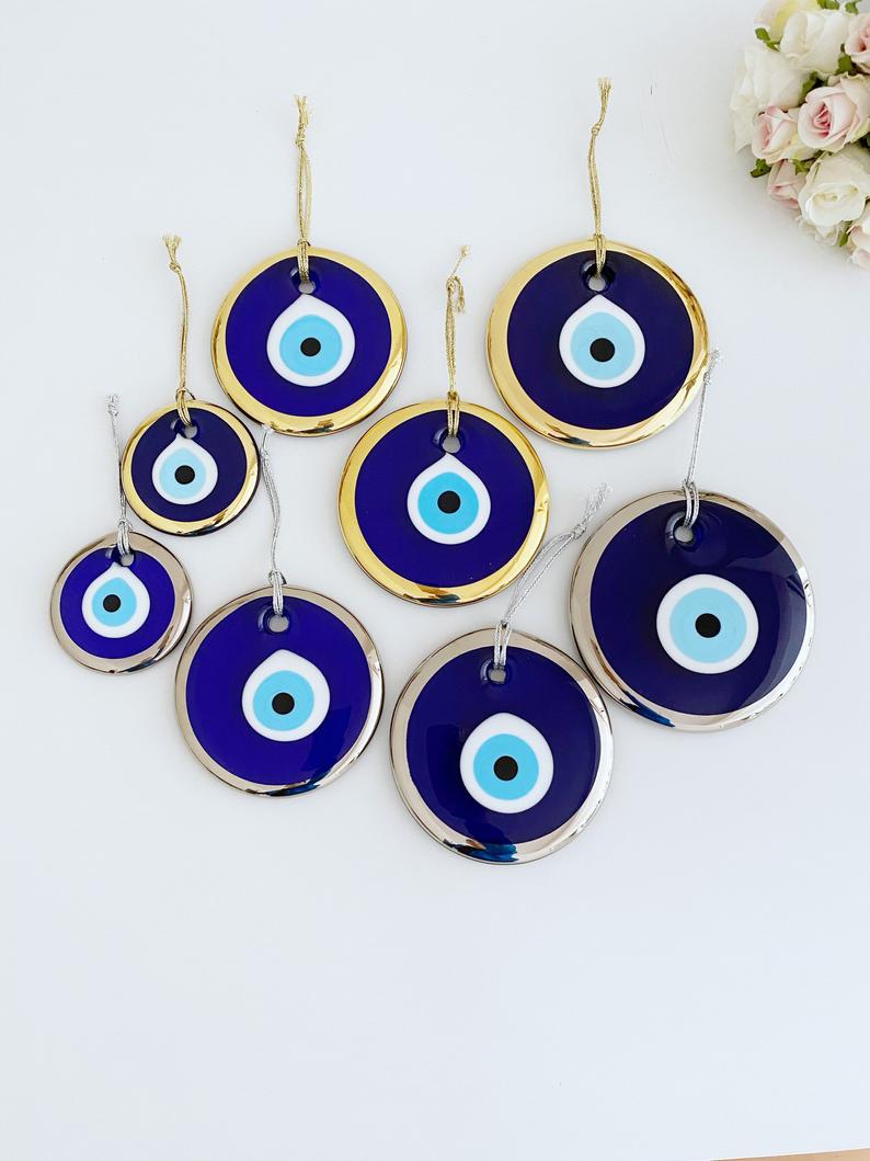 A collection of handmade silver evil eye beads ranging from 7cm to 13cm, showcasing intricate designs and a shiny finish, ready for wall hanging.