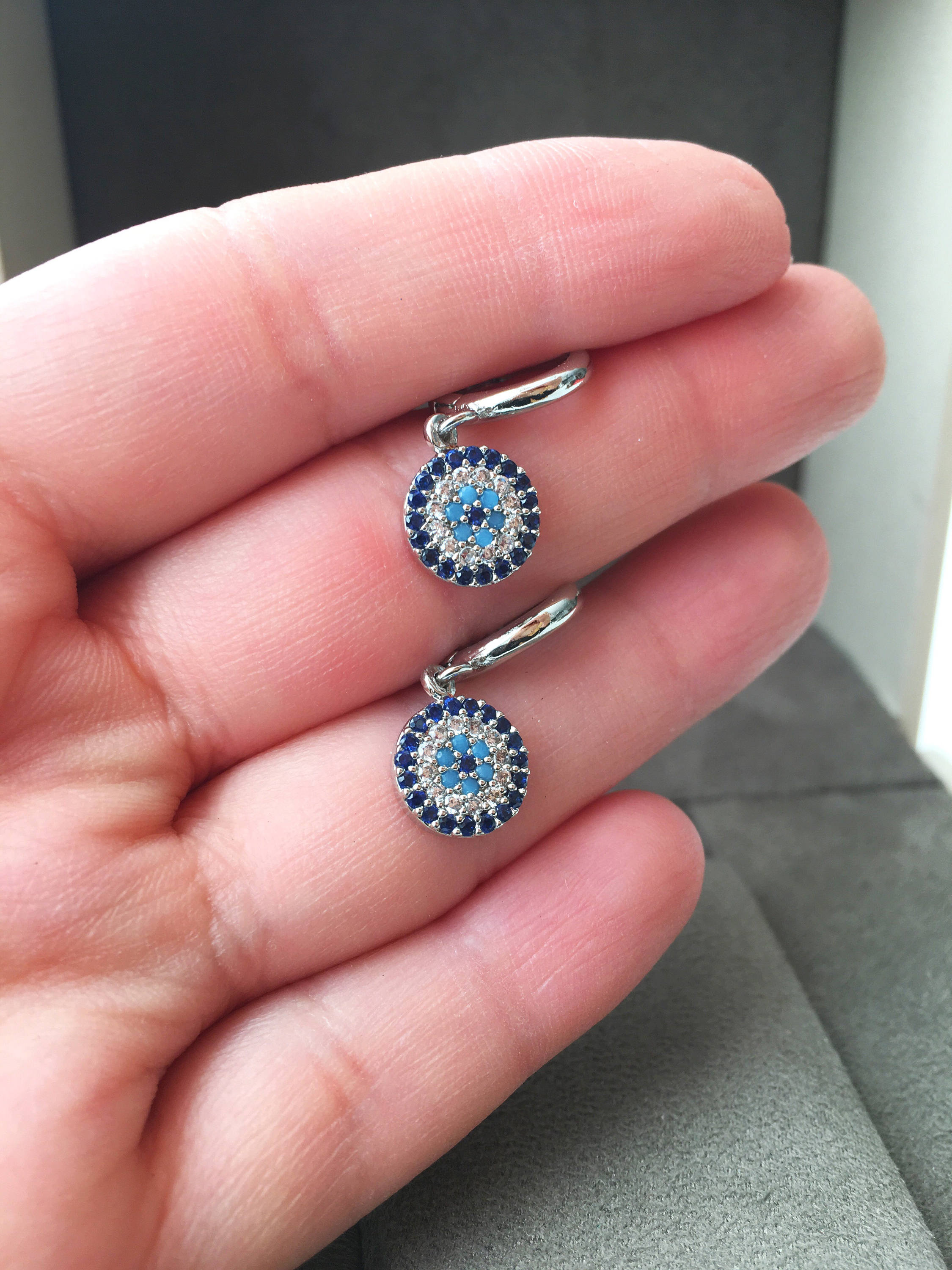 A pair of handmade silver evil eye hoop earrings featuring zircon accents, symbolizing protection and good luck.