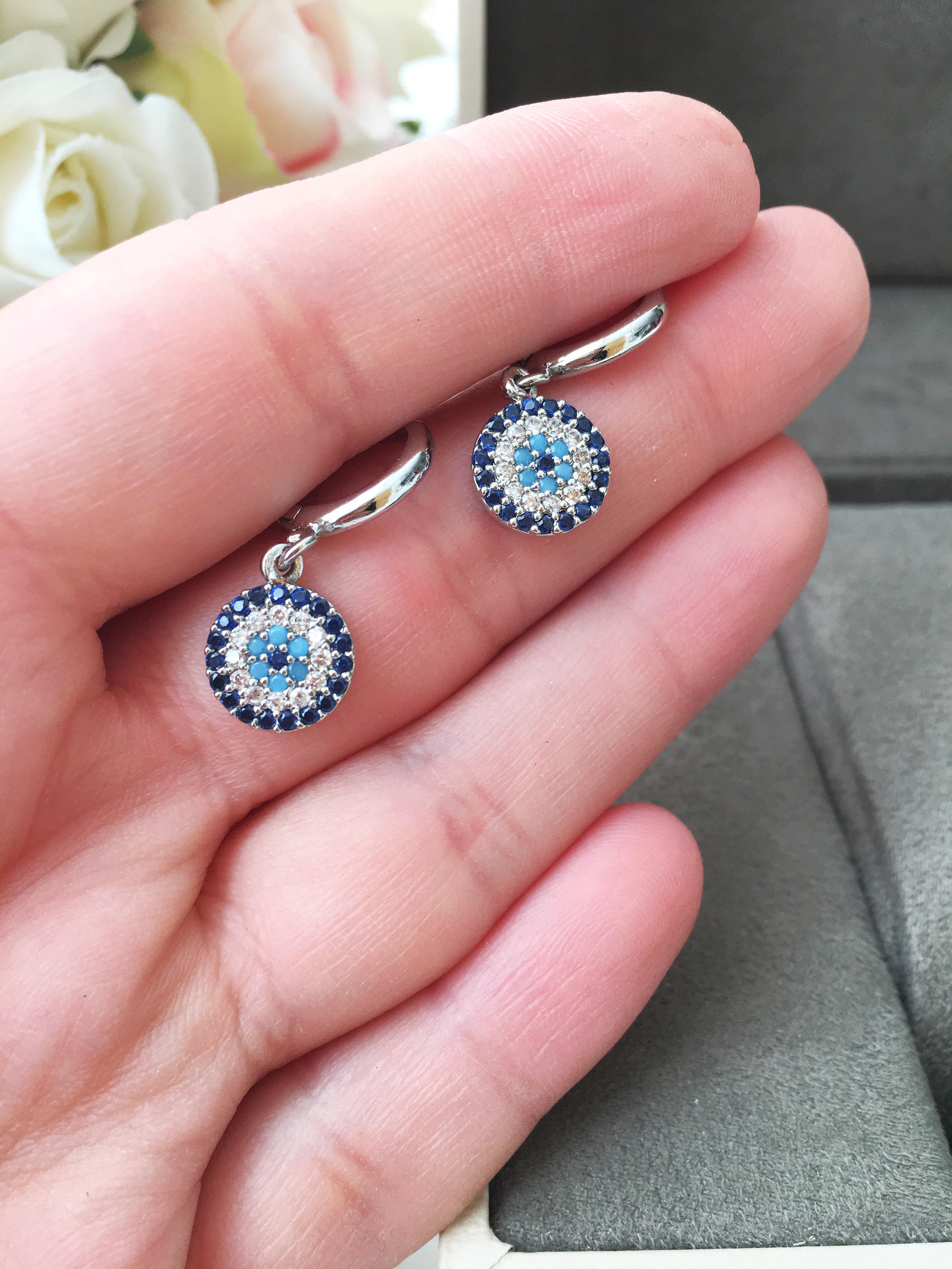 A pair of handmade silver evil eye hoop earrings featuring zircon accents, symbolizing protection and good luck.