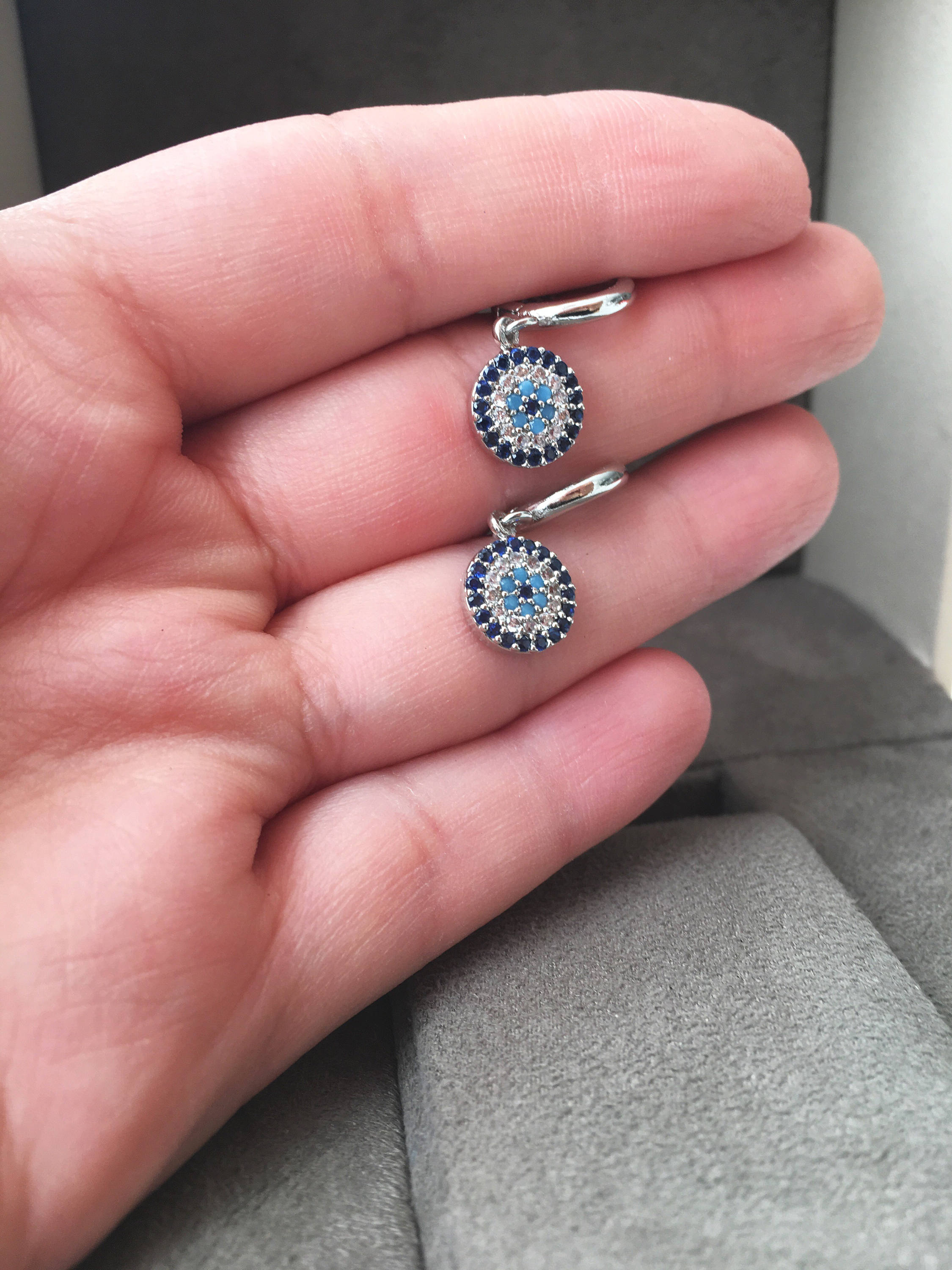 A pair of handmade silver evil eye hoop earrings featuring zircon accents, symbolizing protection and good luck.