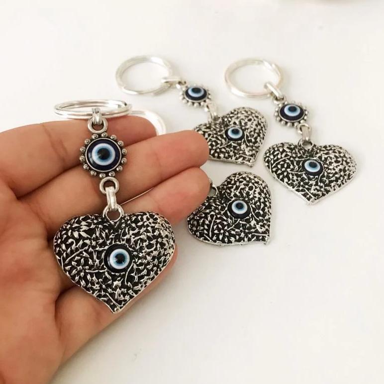 A silver heart keychain featuring an evil eye bead, symbolizing protection and luck.