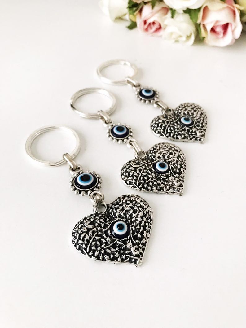 A silver heart keychain featuring an evil eye bead, symbolizing protection and luck.