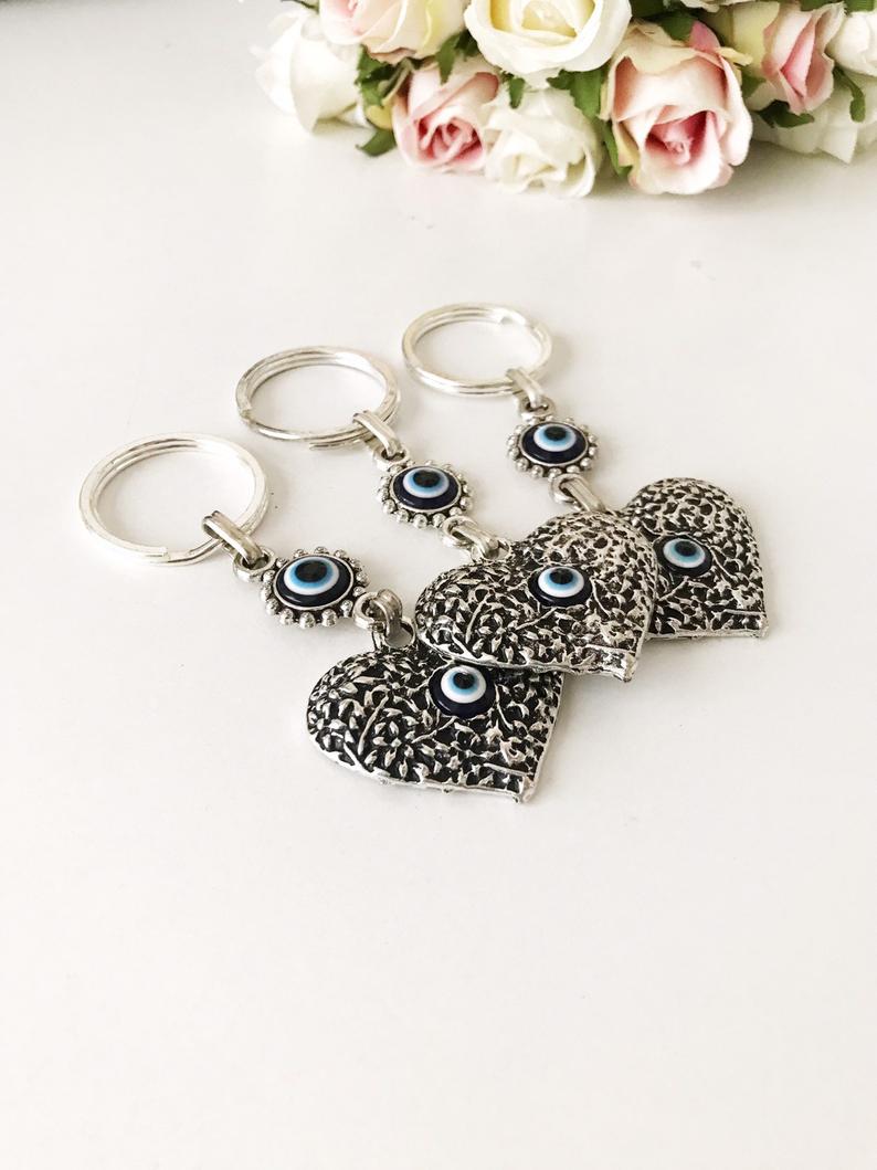 A silver heart keychain featuring an evil eye bead, symbolizing protection and luck.