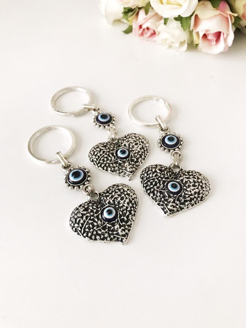 A silver heart keychain featuring an evil eye bead, symbolizing protection and luck.