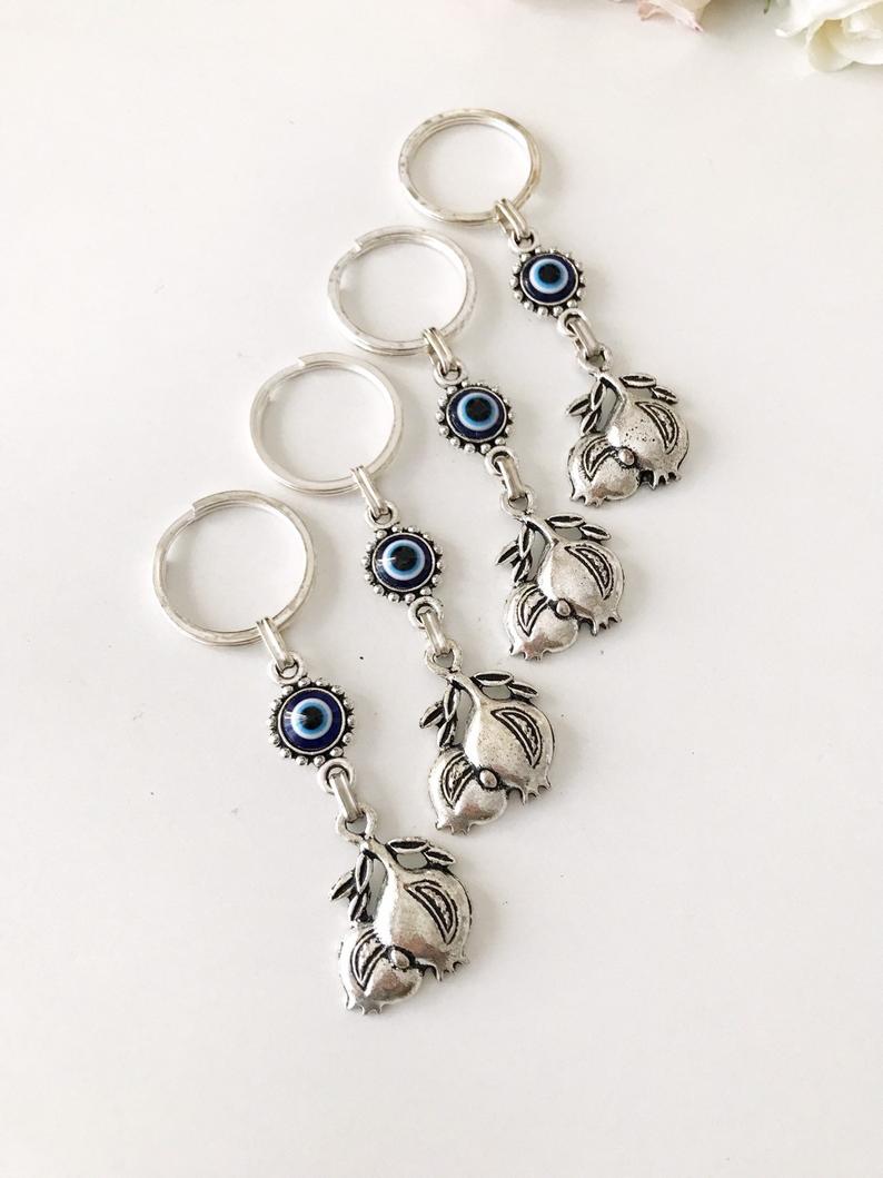 A beautiful silver keychain featuring a pomegranate design with an evil eye symbol, perfect for good luck and charm.