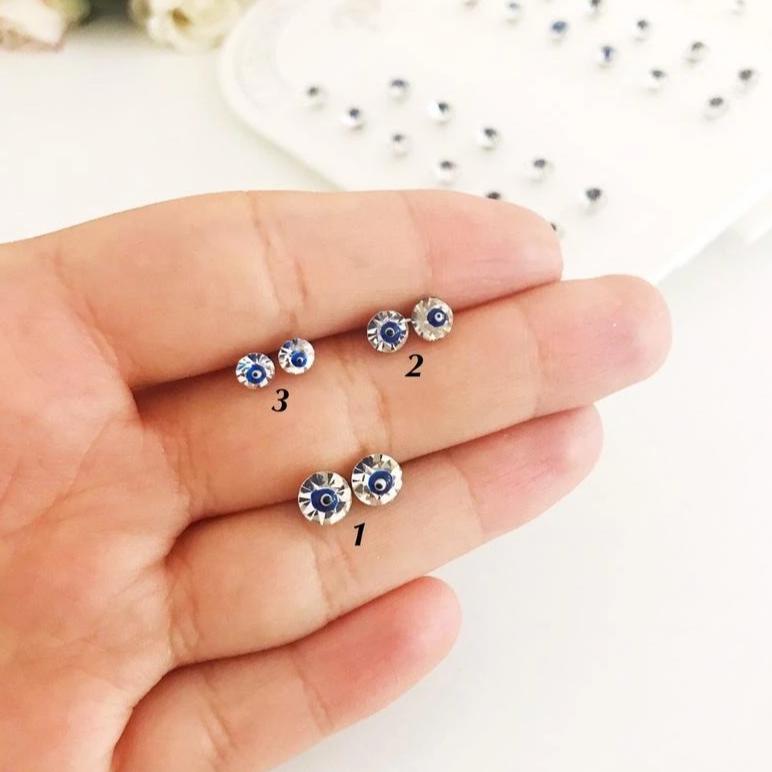 A pair of handmade silver evil eye stud earrings featuring a minimalist design with crystal accents, symbolizing protection.