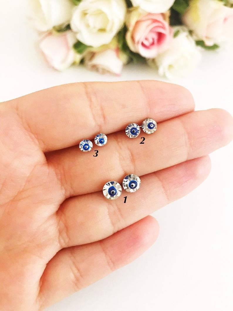 A pair of handmade silver evil eye stud earrings featuring a minimalist design with crystal accents, symbolizing protection.