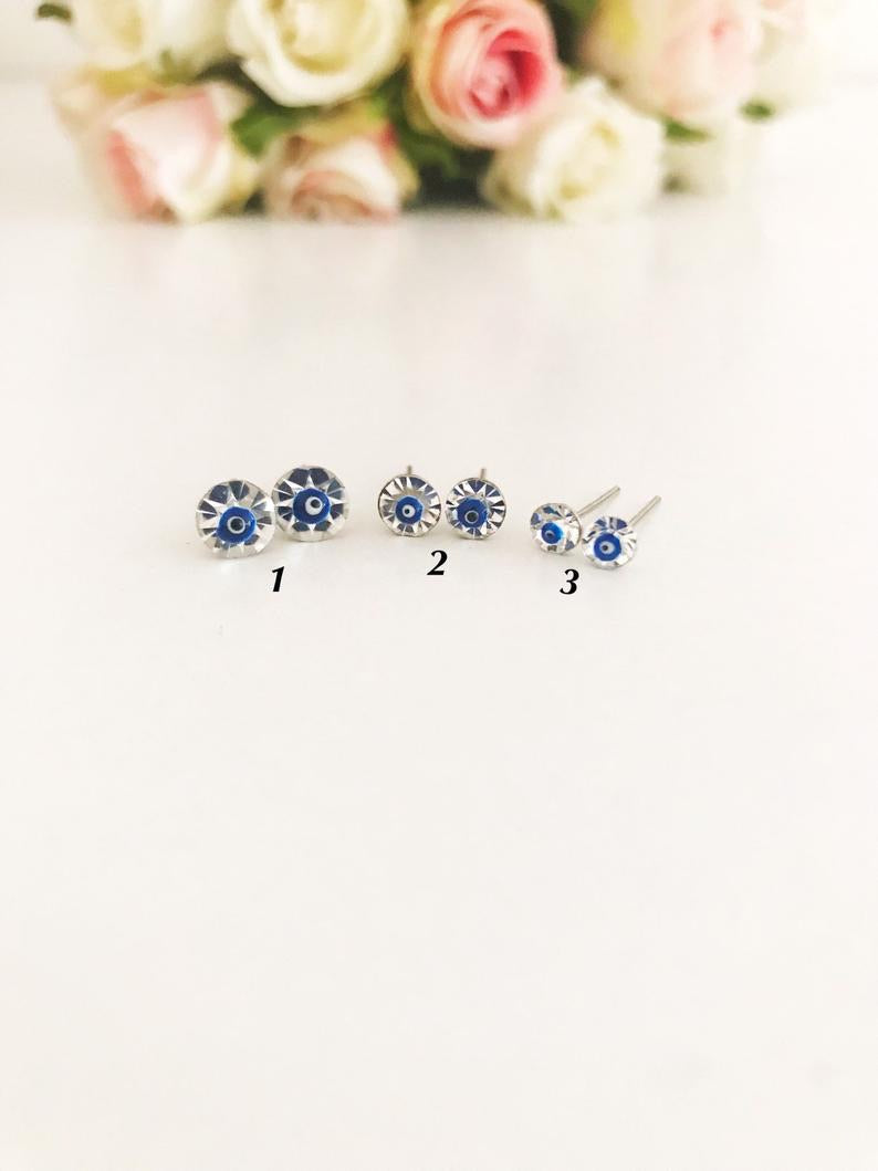 A pair of handmade silver evil eye stud earrings featuring a minimalist design with crystal accents, symbolizing protection.