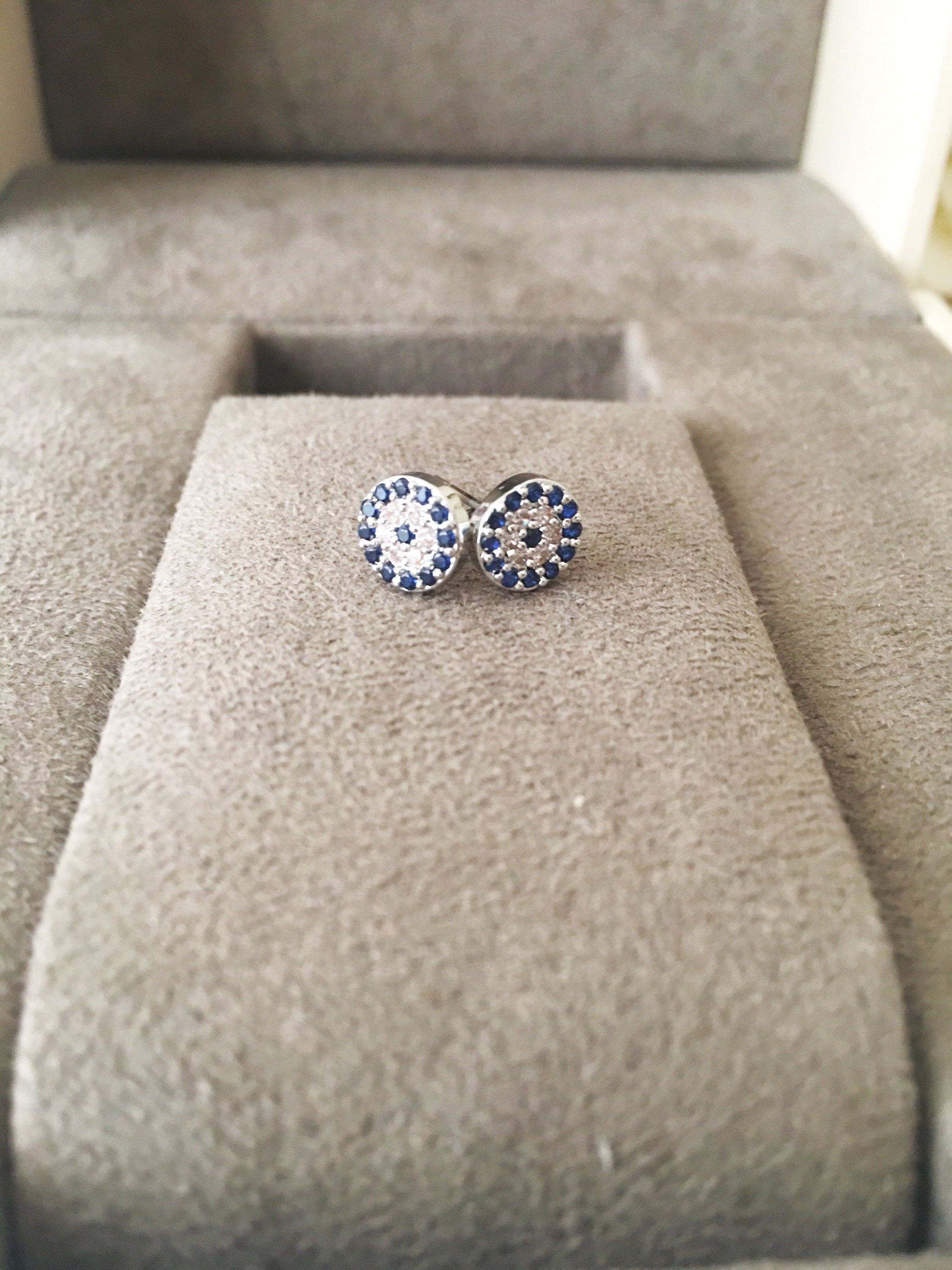 A pair of elegant silver evil eye stud earrings featuring a minimalist design with zircon accents, symbolizing protection.