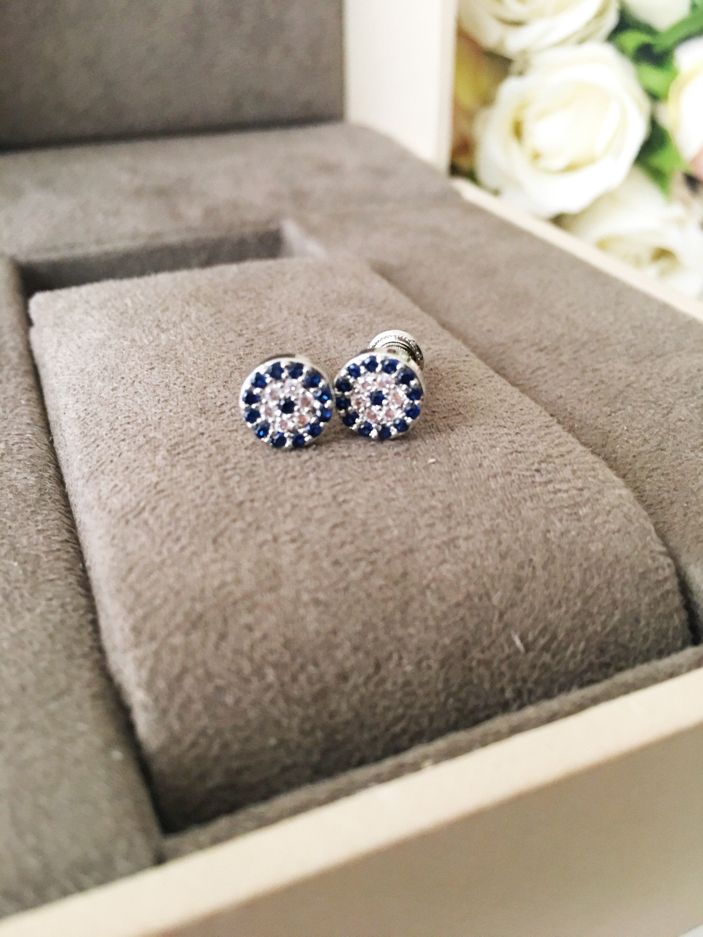 A pair of elegant silver evil eye stud earrings featuring a minimalist design with zircon accents, symbolizing protection.