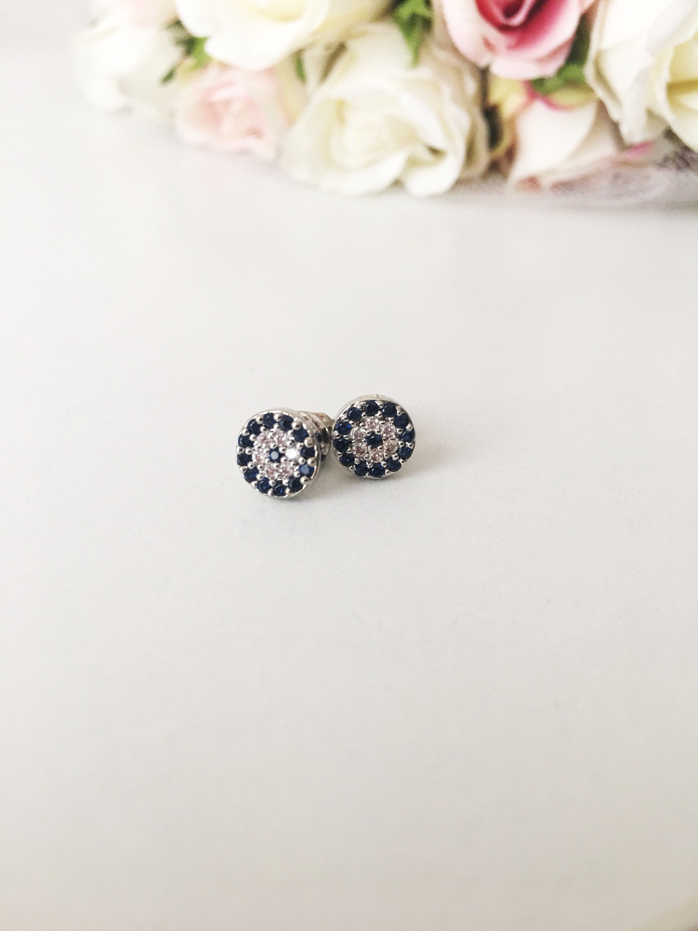 A pair of elegant silver evil eye stud earrings featuring a minimalist design with zircon accents, symbolizing protection.