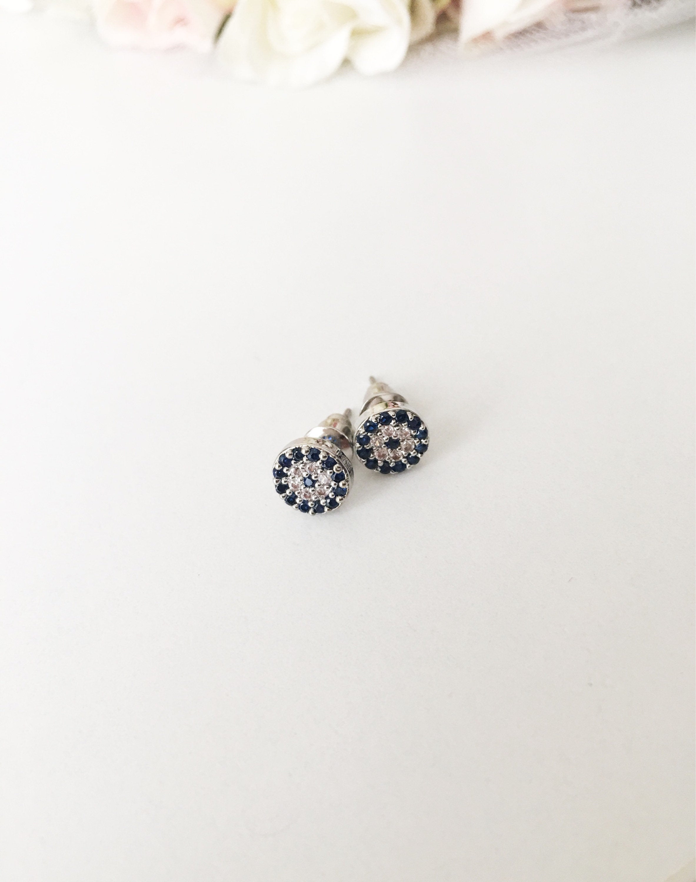 A pair of elegant silver evil eye stud earrings featuring a minimalist design with zircon accents, symbolizing protection.