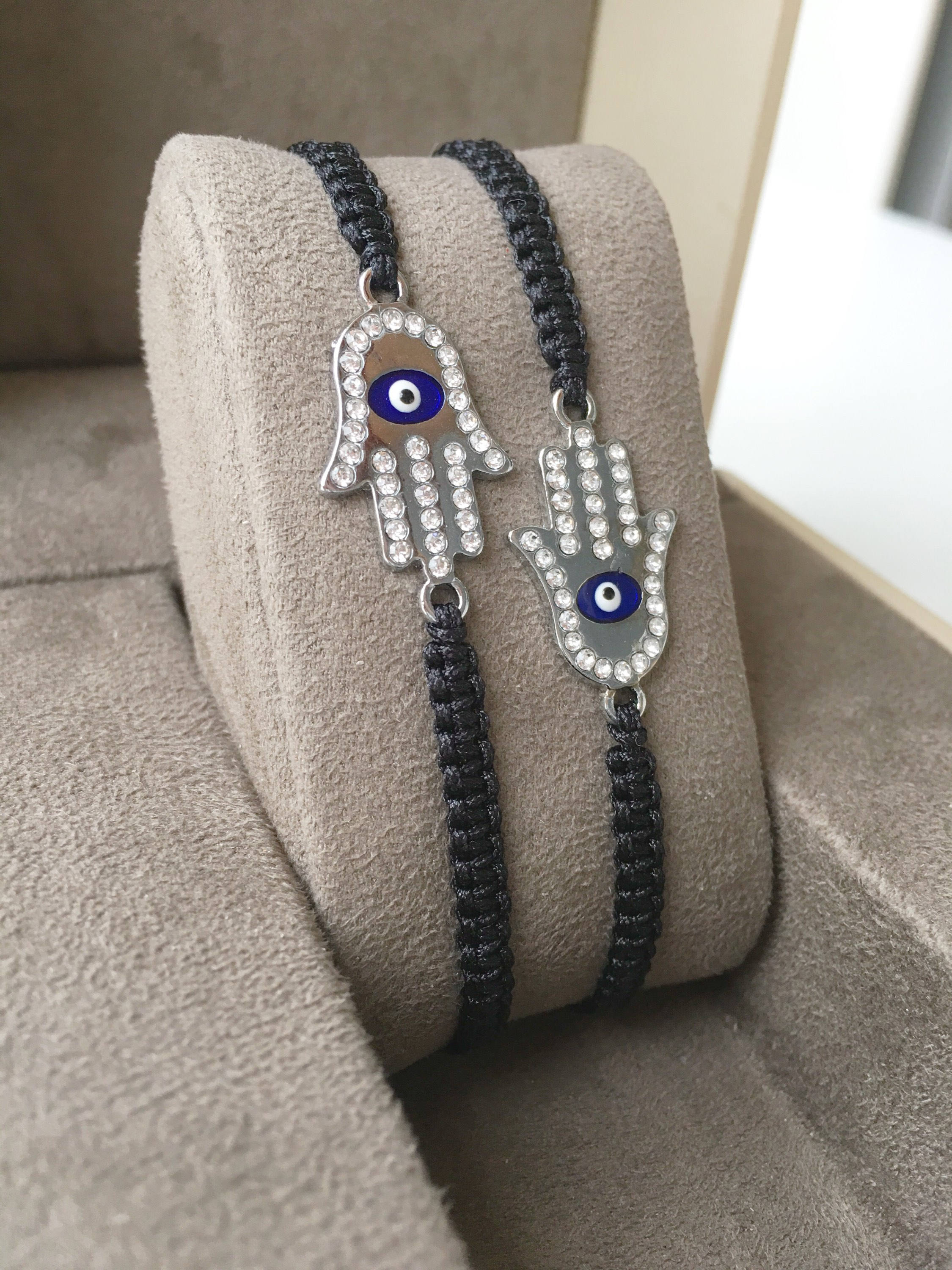 A handmade Silver Hamsa Evil Eye Bracelet featuring a silver zirconia hamsa charm on an adjustable black macrame string.