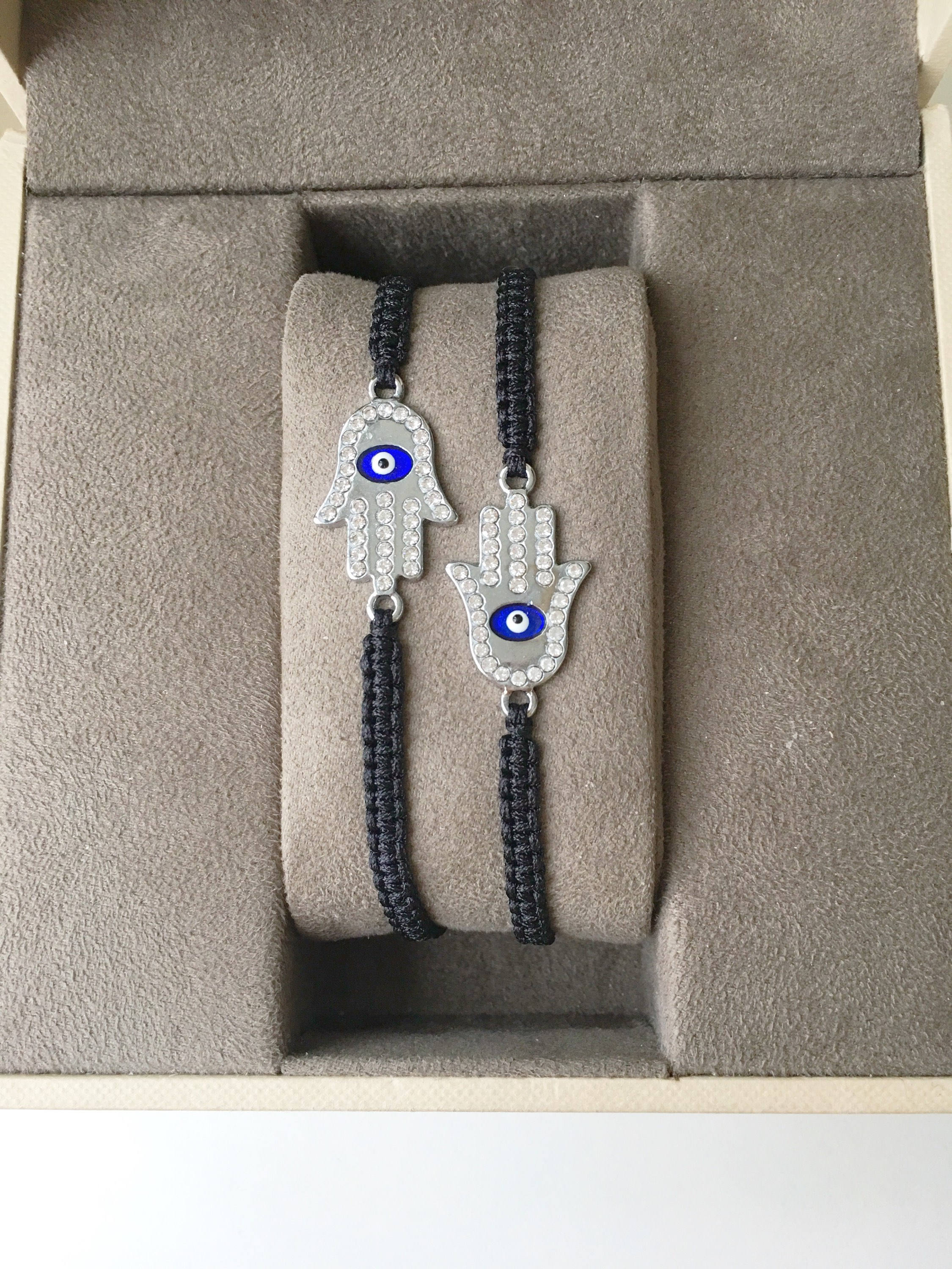 A handmade Silver Hamsa Evil Eye Bracelet featuring a silver zirconia hamsa charm on an adjustable black macrame string.