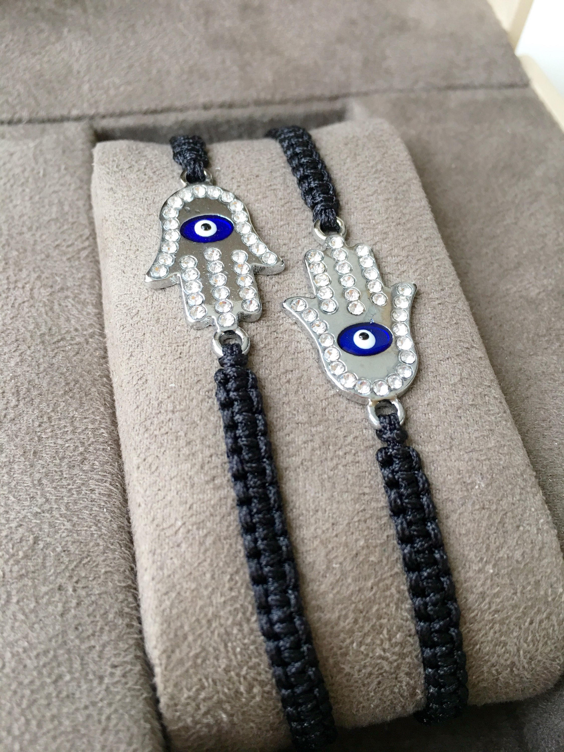 A handmade Silver Hamsa Evil Eye Bracelet featuring a silver zirconia hamsa charm on an adjustable black macrame string.