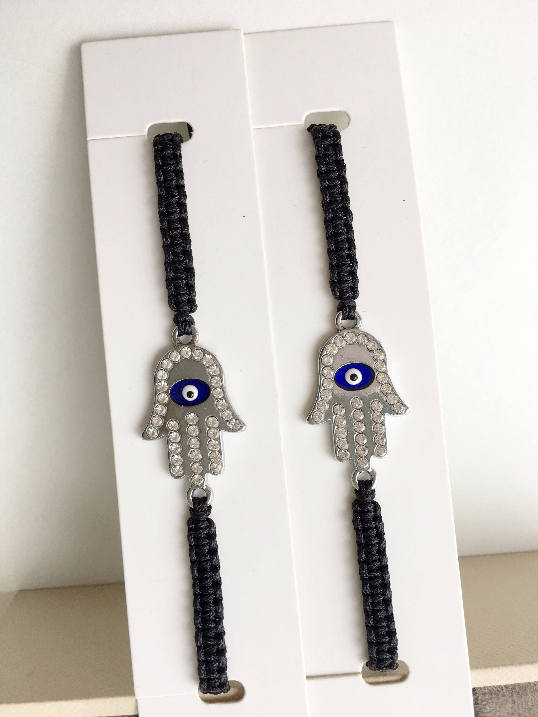 A handmade Silver Hamsa Evil Eye Bracelet featuring a silver zirconia hamsa charm on an adjustable black macrame string.