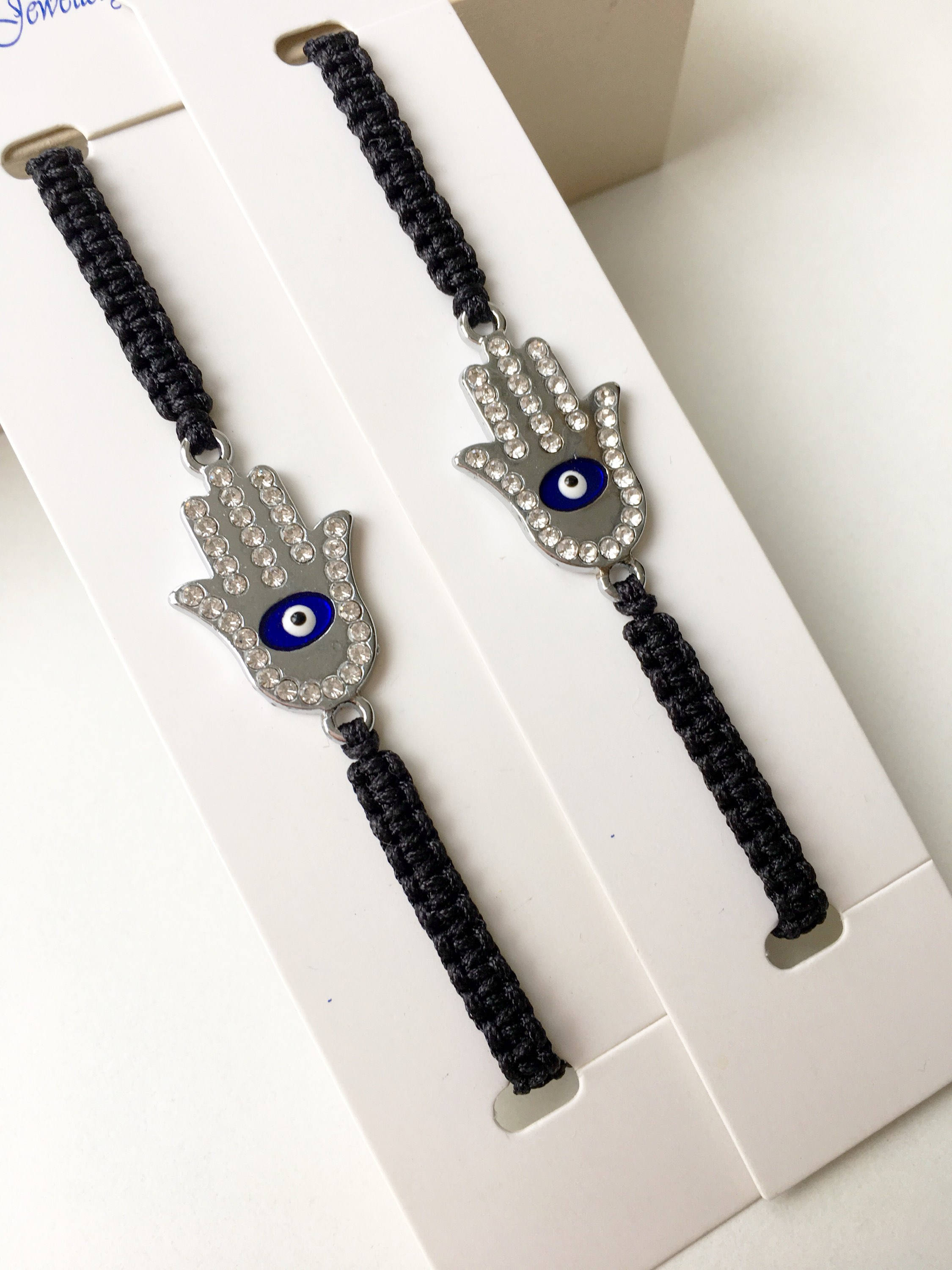 A handmade Silver Hamsa Evil Eye Bracelet featuring a silver zirconia hamsa charm on an adjustable black macrame string.