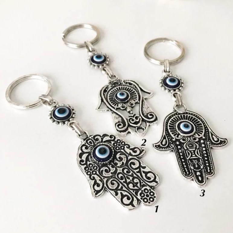 A beautiful silver hamsa keyring featuring handmade blue glass evil eye beads, symbolizing protection and good luck.