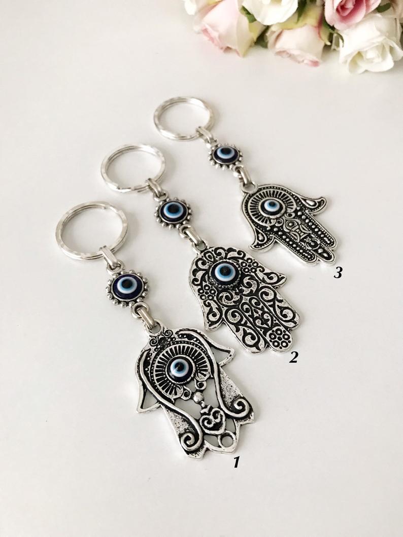 A beautiful silver hamsa keyring featuring handmade blue glass evil eye beads, symbolizing protection and good luck.